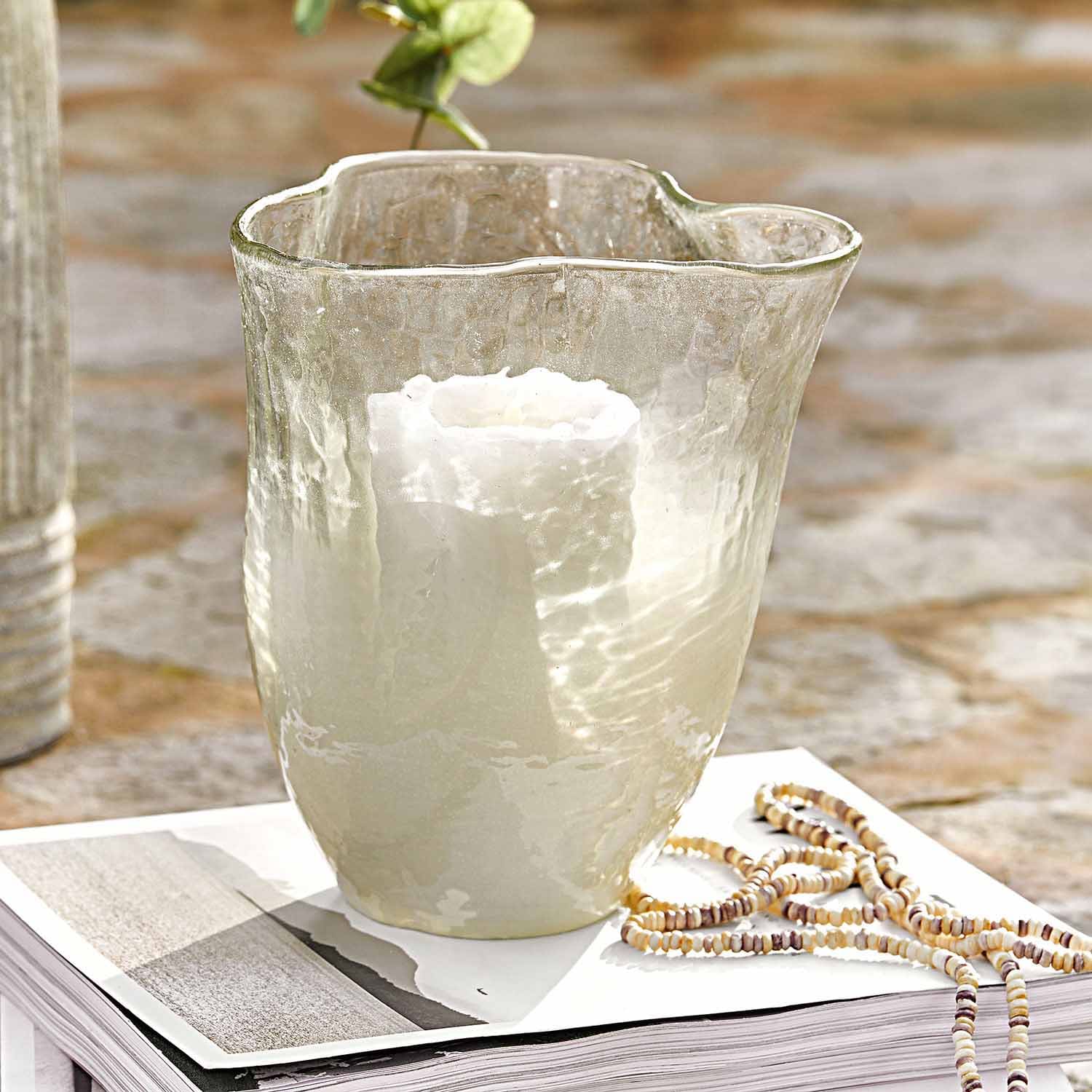 Photophore en verre transparent avec bougie blanche posé sur un livre ouvert, décoration intérieure