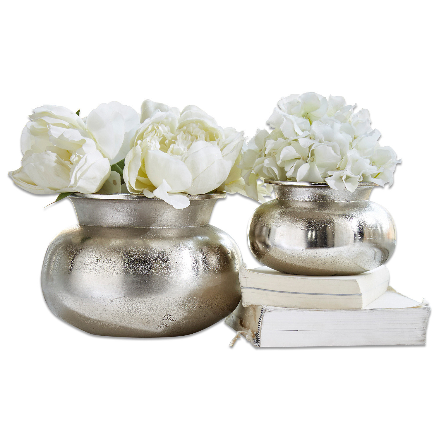 Lot de 2 vases Clément Deux vases en métal argenté avec fleurs blanches posés sur des livres blancs, décoration élégante