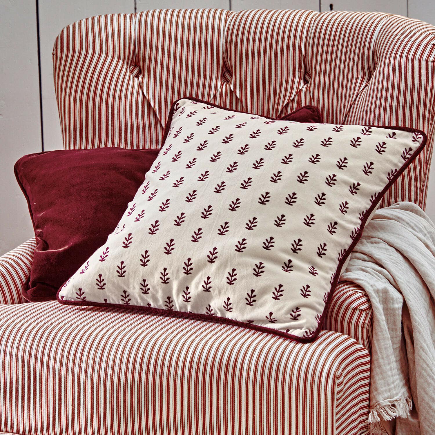 Lot de 2 housses de coussins Eilira Fauteuil rayé rouge et blanc avec coussins bordeaux et plaid clair pour salon cosy