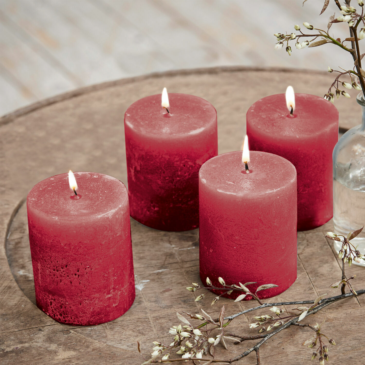 Lot de 4 bougies Virrans Quatre bougies rouges en cire sur une table en bois avec décoration florale, ambiance cosy