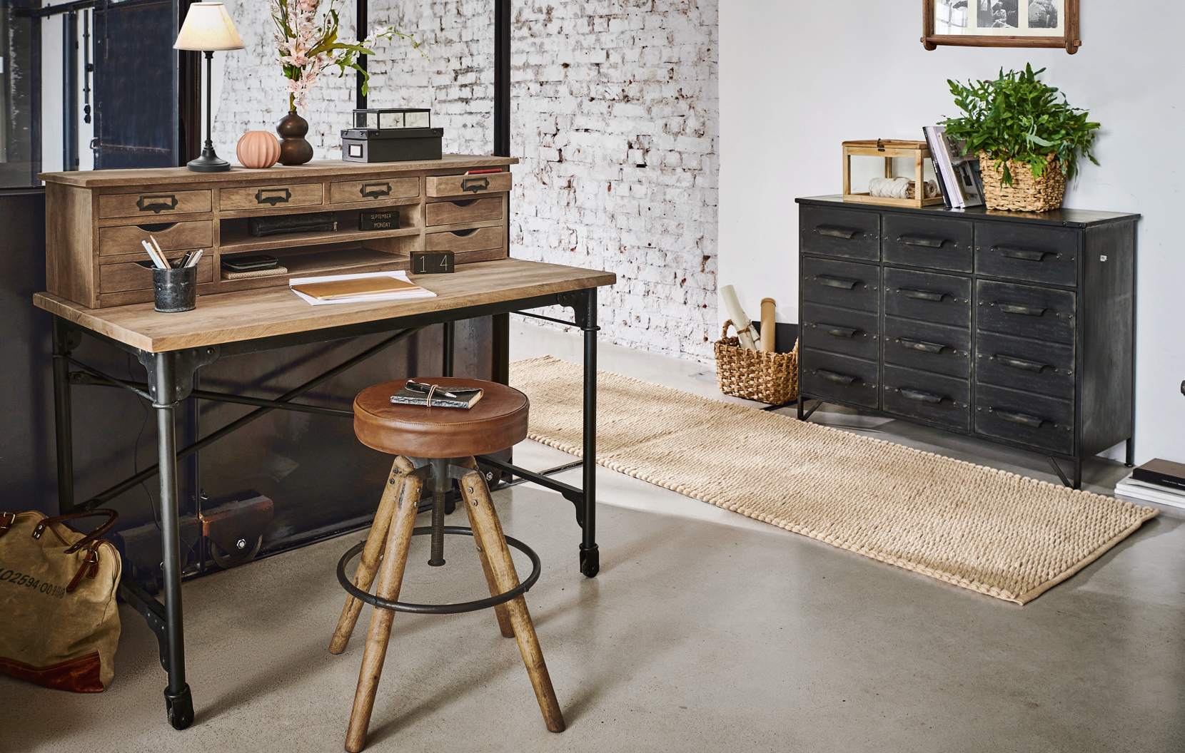 Bureau industriel en bois et métal avec plusieurs tiroirs et tabouret en cuir vintage dans un intérieur moderne