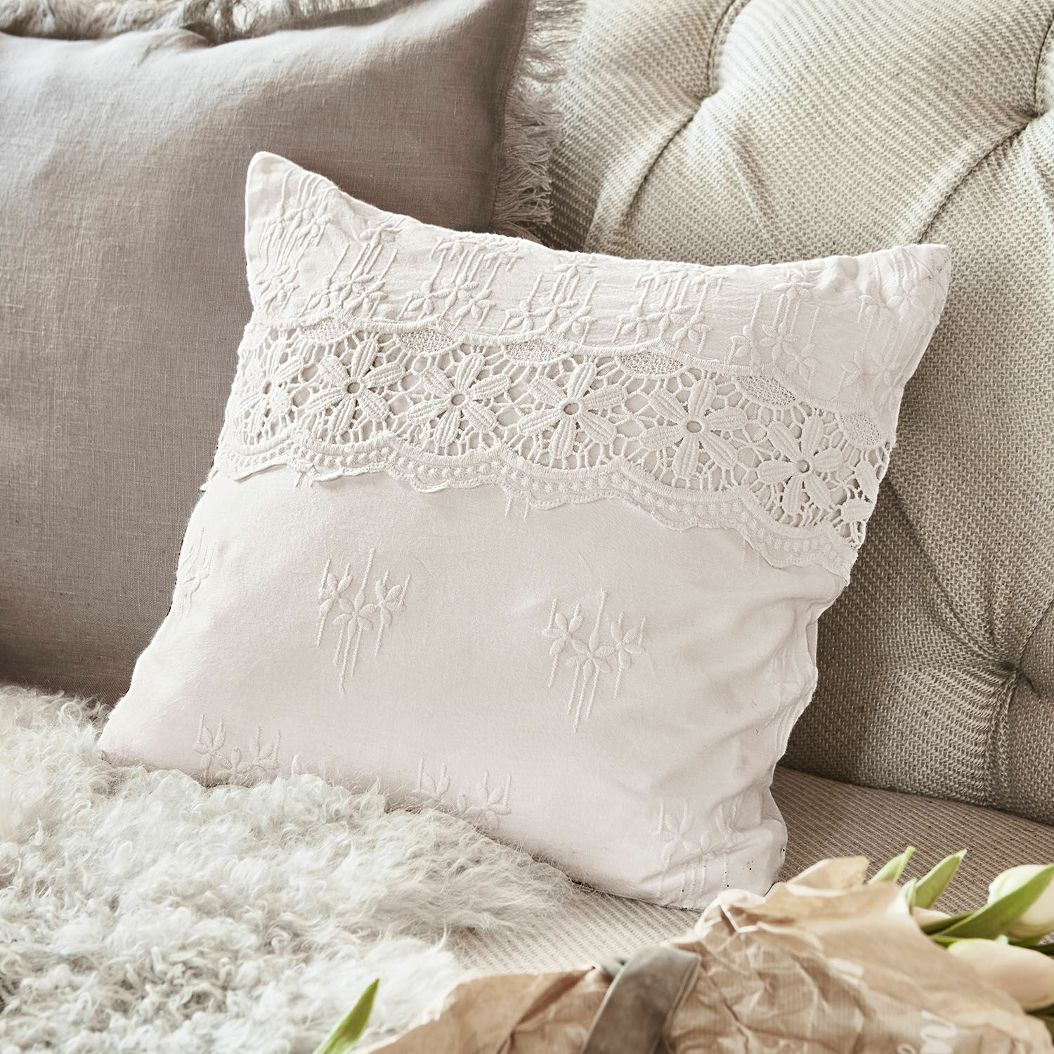 Housse de coussin Fianna Coussin décoratif beige en tissu doux avec dentelle et broderie, ambiance cosy sur canapé