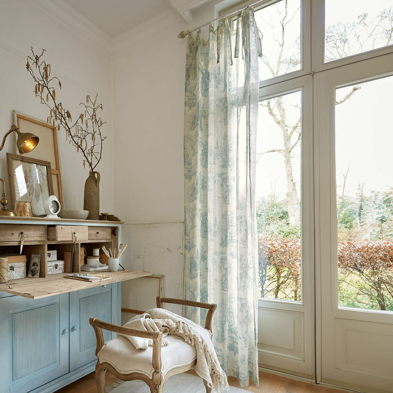 Rideau Dedwen Coin cosy avec buffet en bois bleu et rideau à motif bleu clair dans un salon lumineux avec grande fenêtre