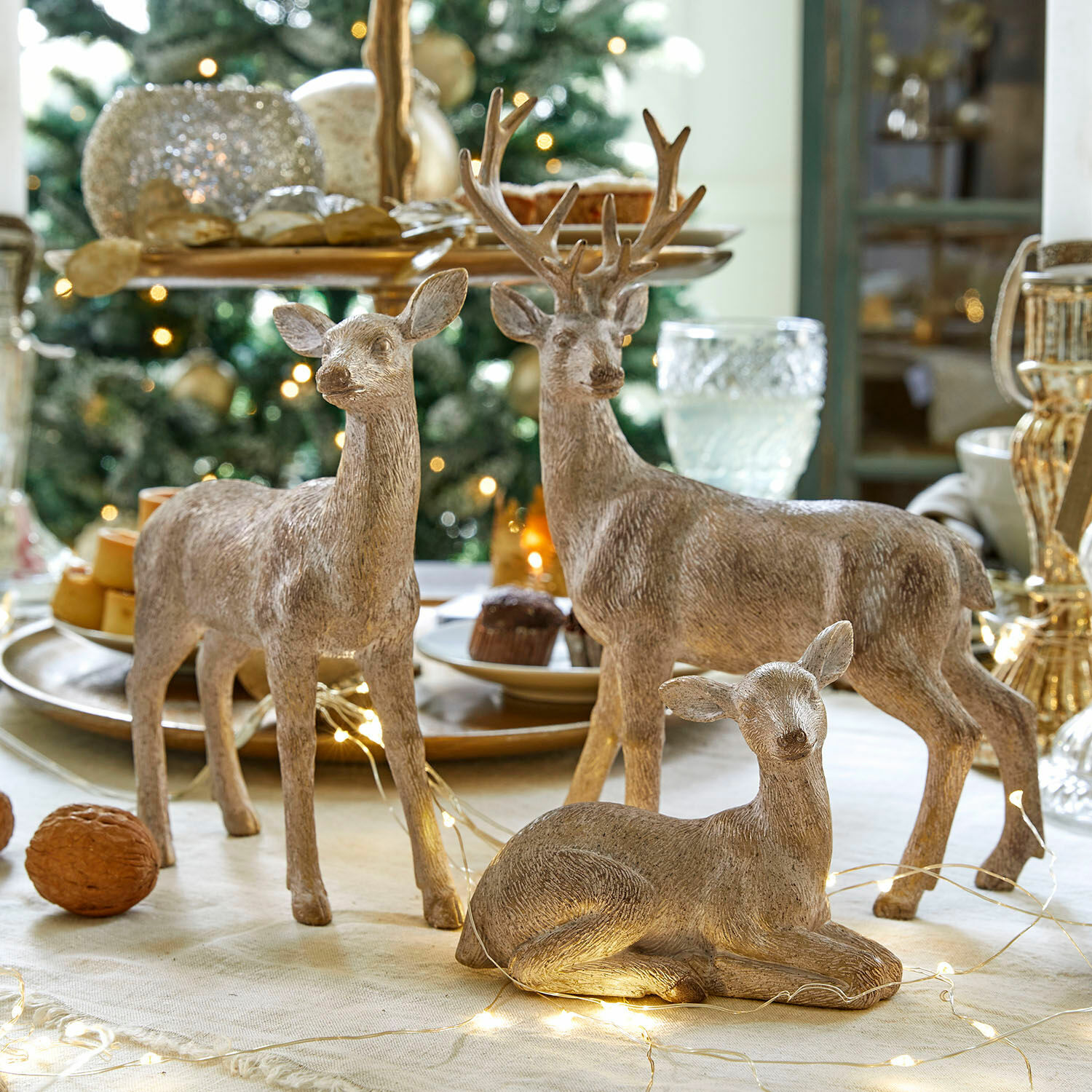 Lot de 3 figurines décoratives Yasirah Ensemble de trois cerfs décoratifs en bois couleur naturelle sur une table de Noël avec guirlandes LED