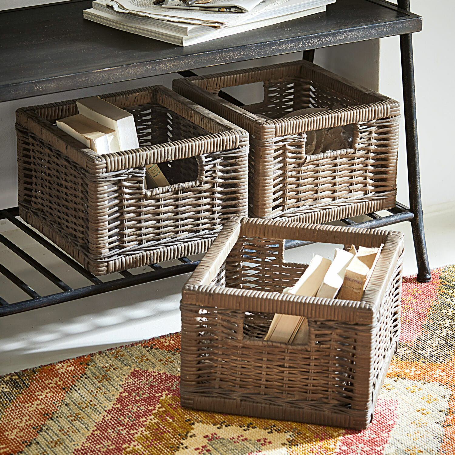 Lot de 3 corbeilles Morvan Trois paniers en rotin marron pour rangement sur une étagère métallique avec livres et tapis coloré