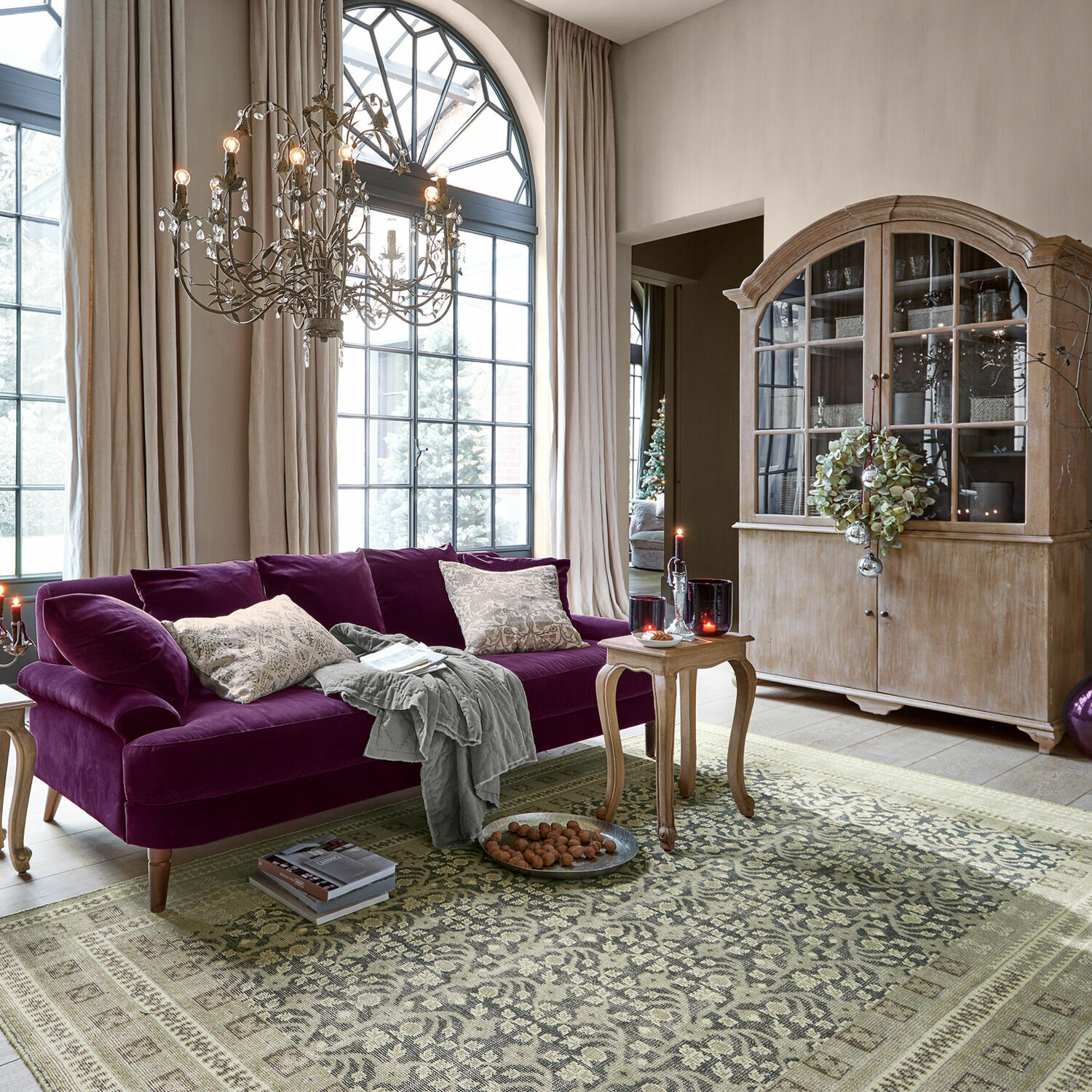 Tapis Nadimah Salon avec canapé violet en velours et vitrine en bois devant grandes fenêtres et tapis à motif