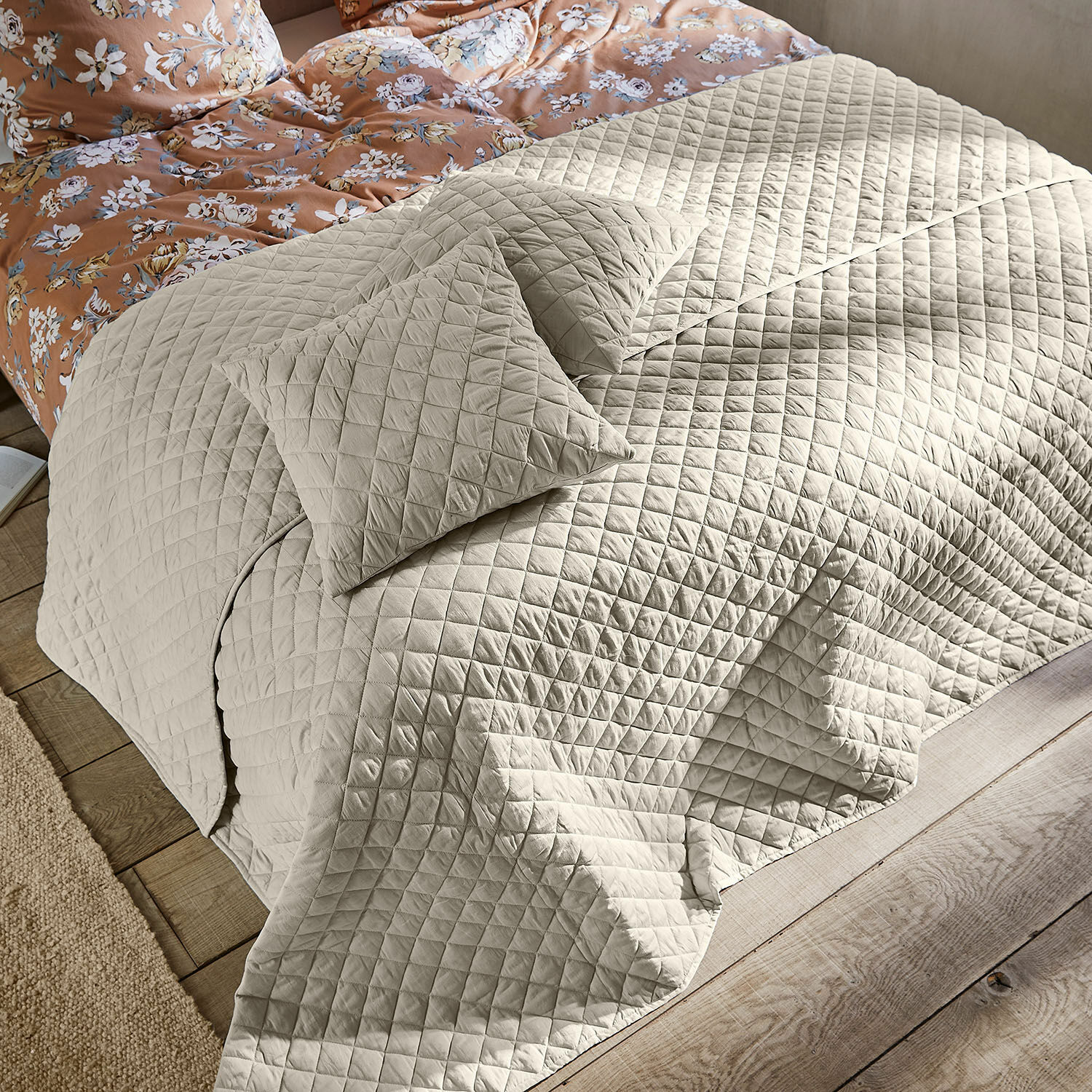 Courtepointe Jolique Couvre-lit matelassé beige avec coussins sur lit en bois et linge de lit à fleurs