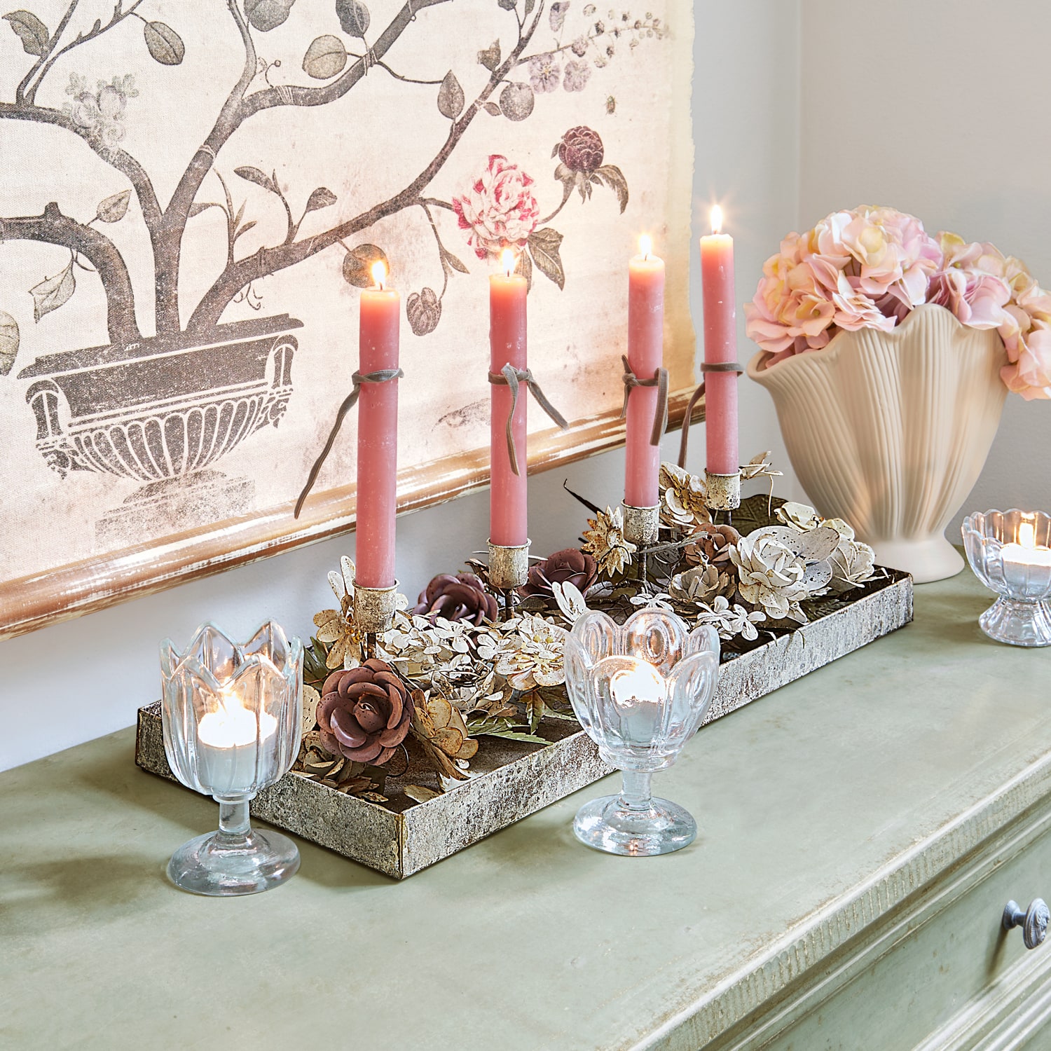 Bougeoir décoratif en métal avec fleurs et bougies roses sur commode verte avec vase à fleurs