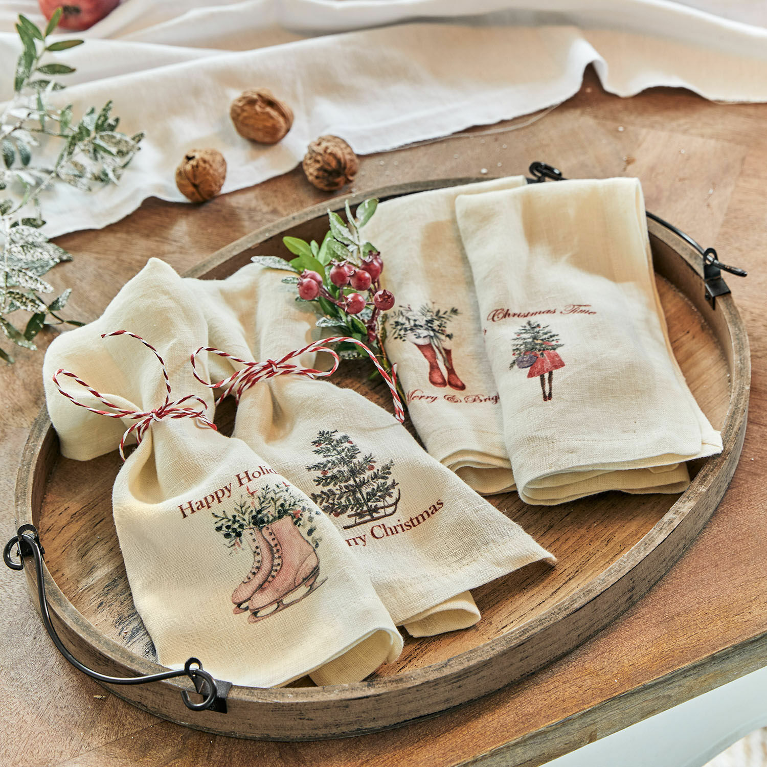 Lot de 4 serviettes Merry & Bright Torchons en lin crème avec motifs de Noël et cordon rouge sur plateau en bois rustique