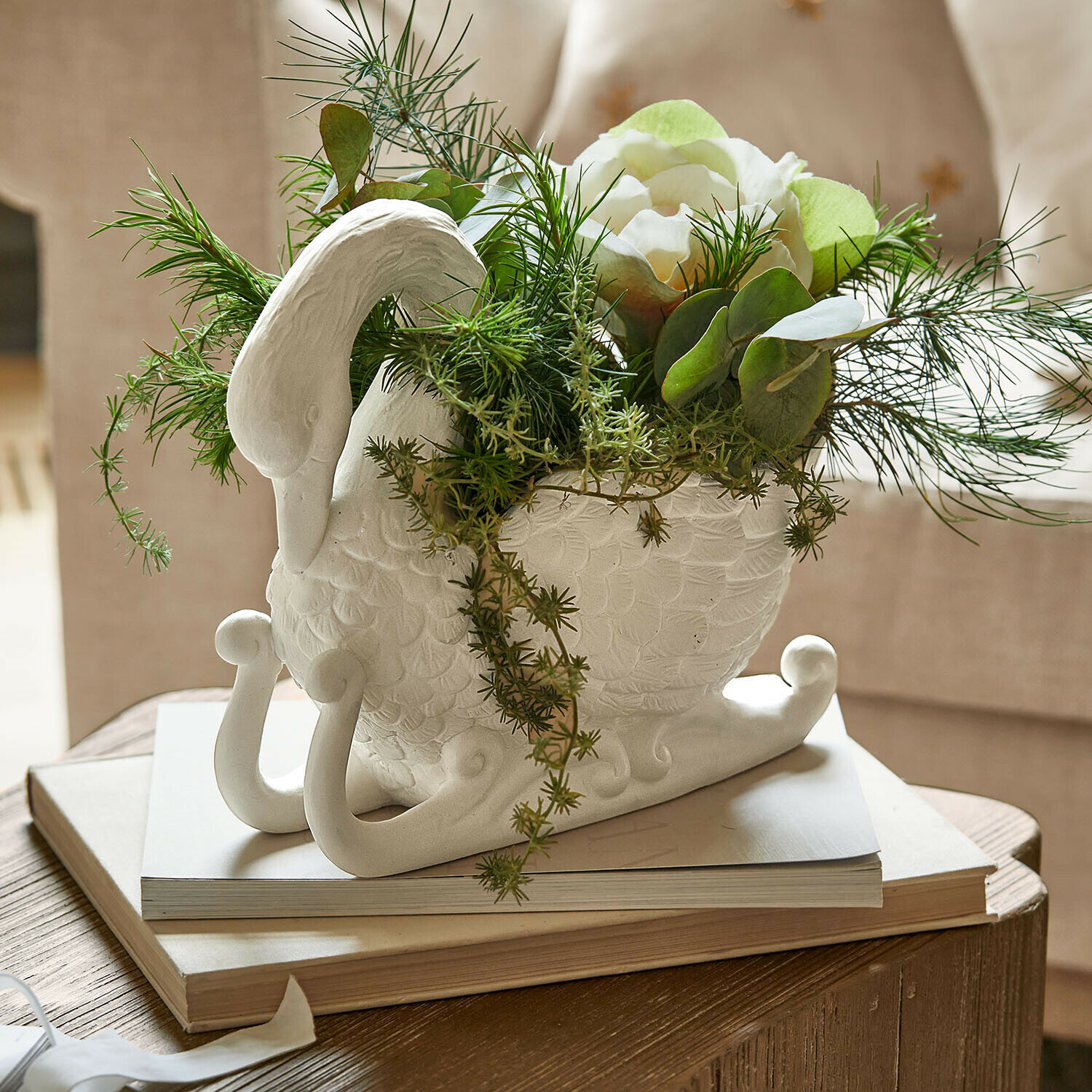 Cache-pot Elarin Vase en céramique blanche en forme de cygne avec fleurs blanches et feuillage vert sur table en bois