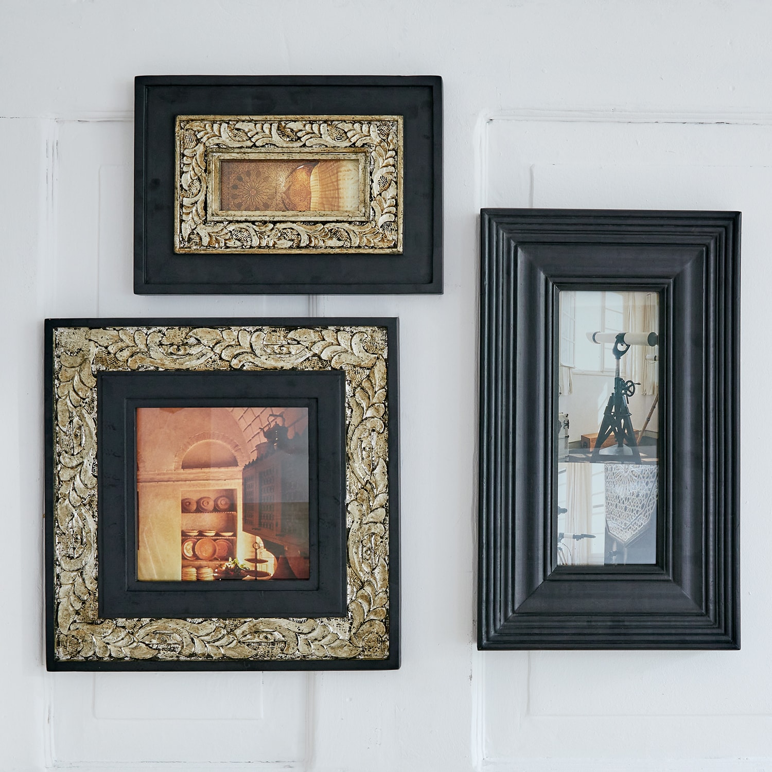 Ensemble de trois cadres noirs avec détails dorés et photos vintage accrochés au mur blanc