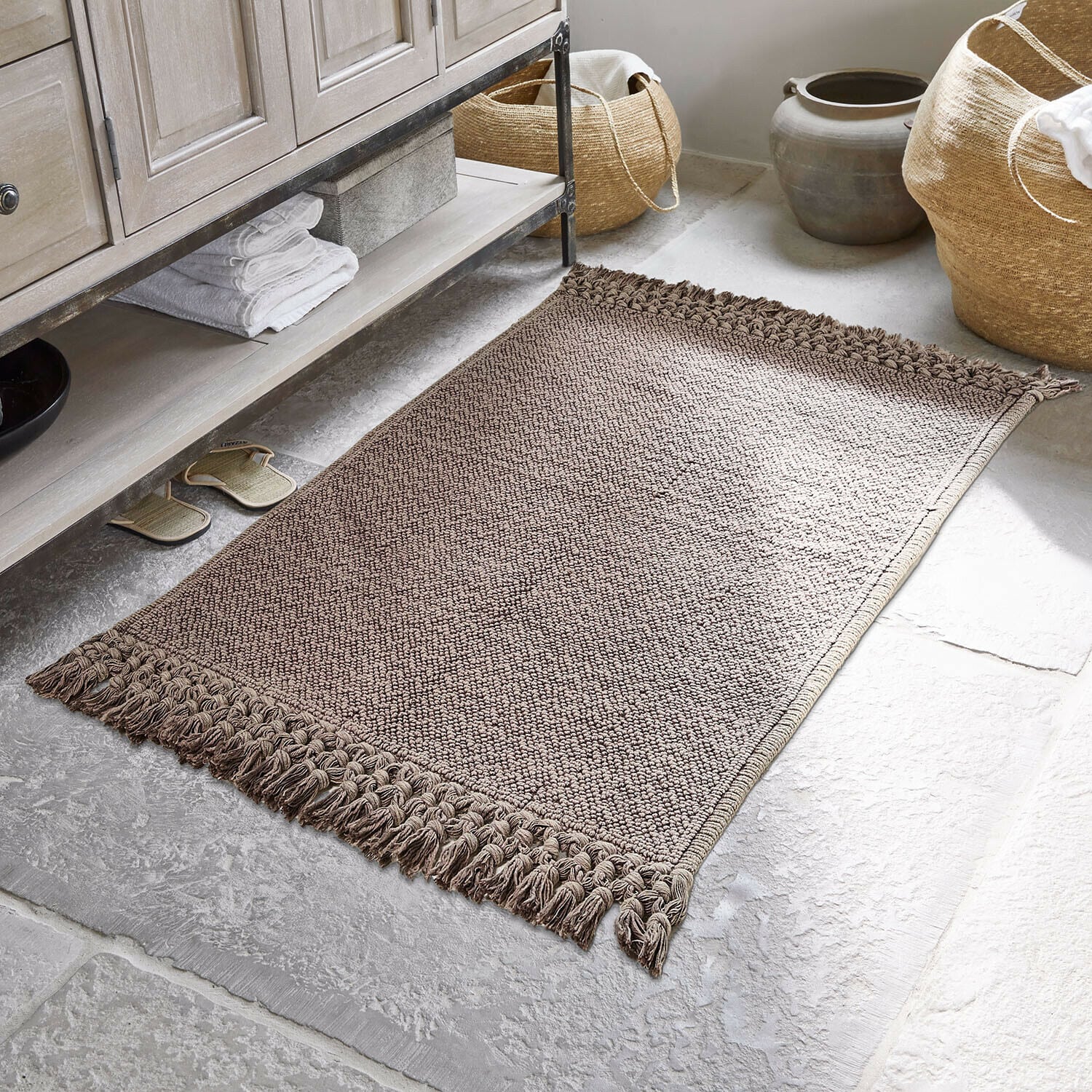 Tapis de bain Faelwyn Tapis en coton marron avec franges sur sol en pierre dans une salle de bain élégante