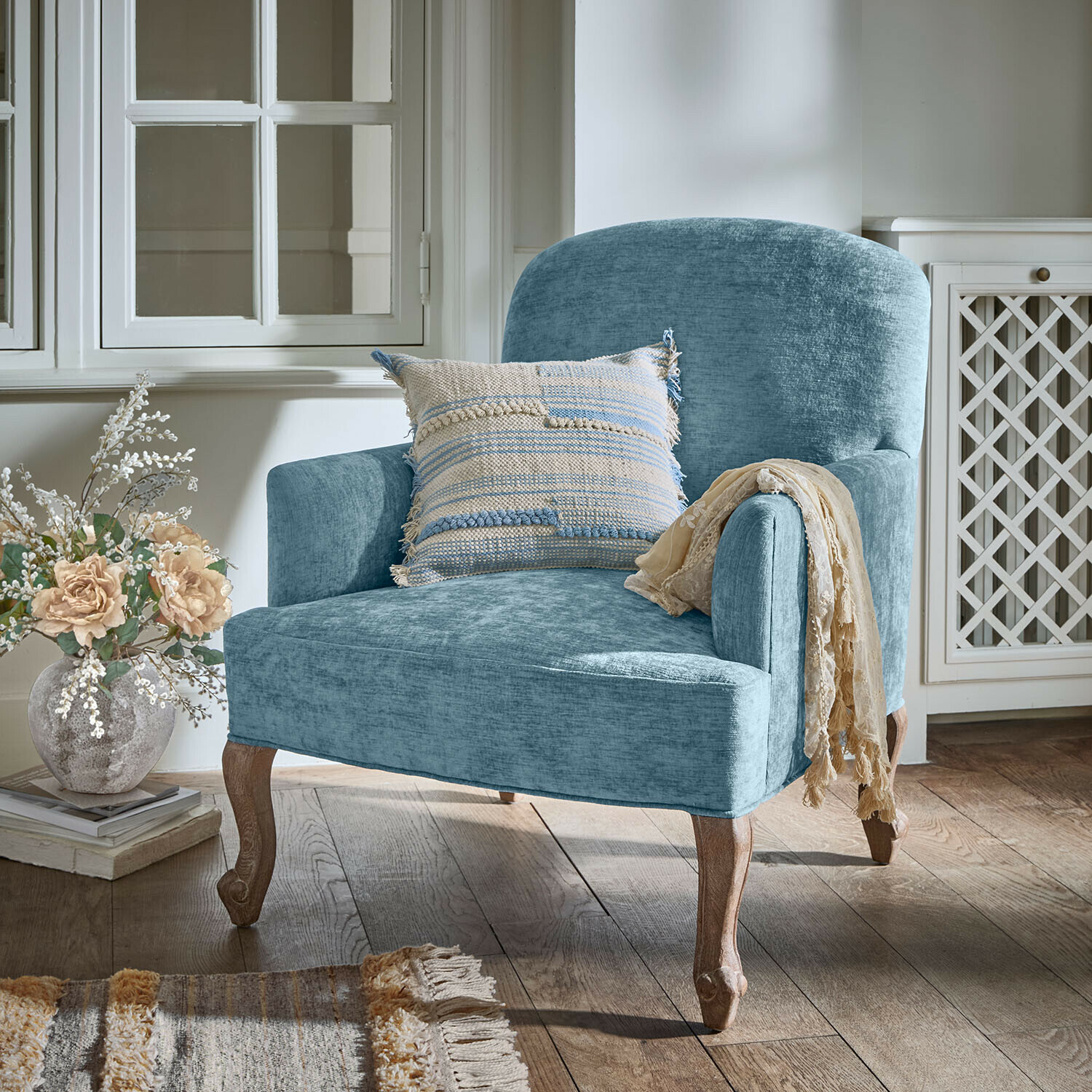 Fauteuil Clairmont Bleu Fauteuil bleu en tissu avec pieds en bois et coussin décoratif dans un intérieur chaleureux