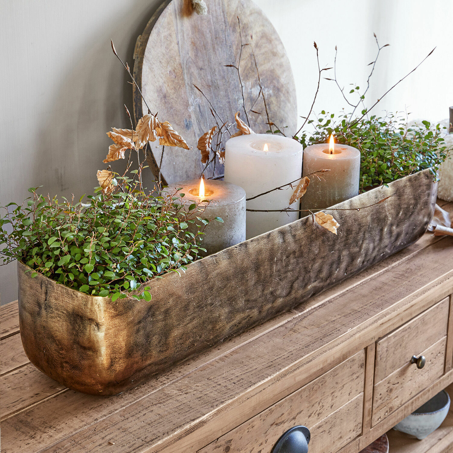 Coupe Skye Jardinière décorative en métal doré avec plantes vertes et trois bougies sur table en bois