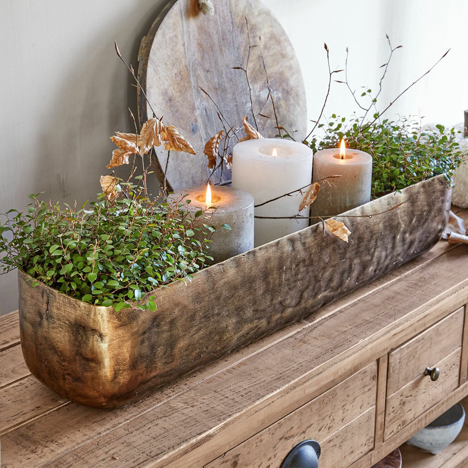 Coupe Skye Jardinière décorative en métal doré avec plantes vertes et trois bougies sur table en bois