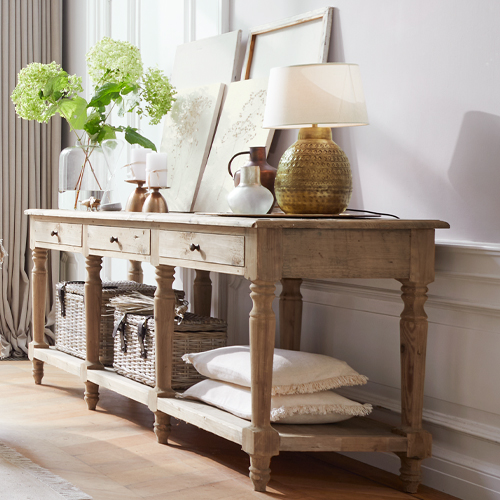 Console en bois naturel avec décorations et lampe posée sur un sol clair dans un intérieur élégant
