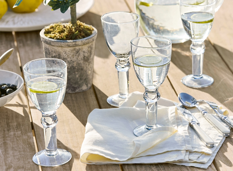 Verres d'eau avec citron sur table en bois, serviette blanche et couverts, ambiance méditerranéenne