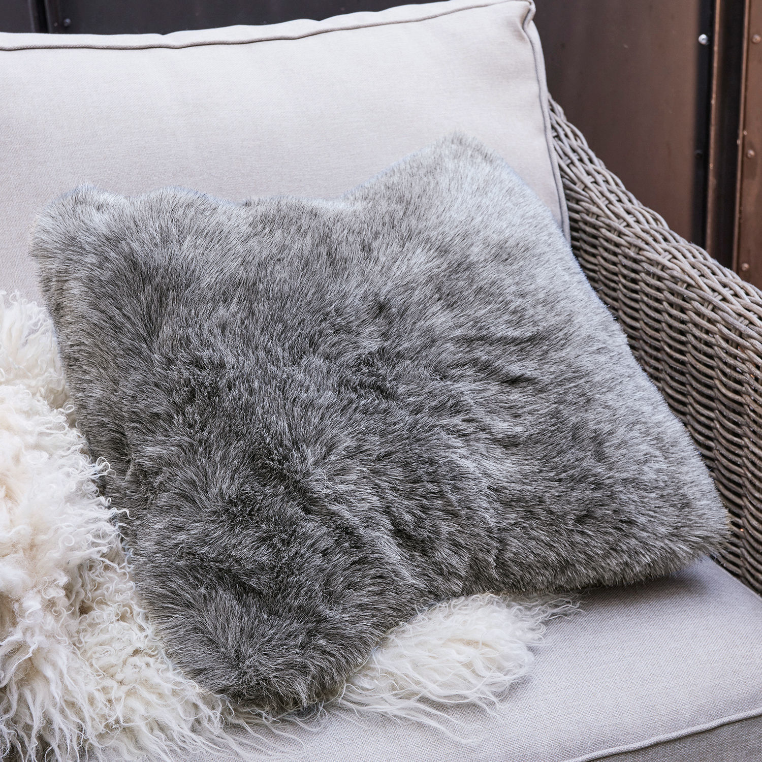 Housse de coussin Bénaix Coussin gris en fausse fourrure douce sur canapé clair, décoration intérieure confortable