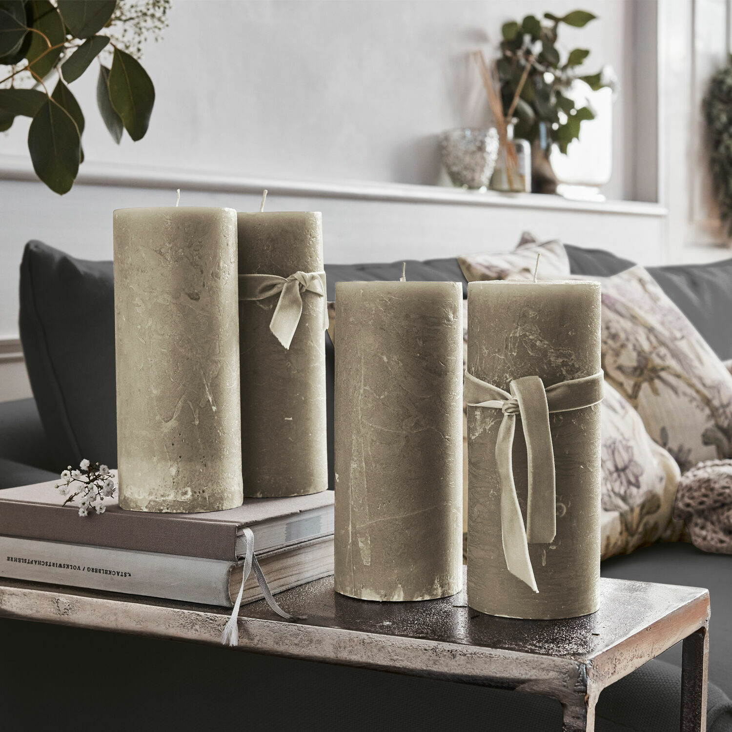 Lot de 4 bougies Homel Ensemble de quatre bougies décoratives beige avec rubans sur une table en métal dans un salon