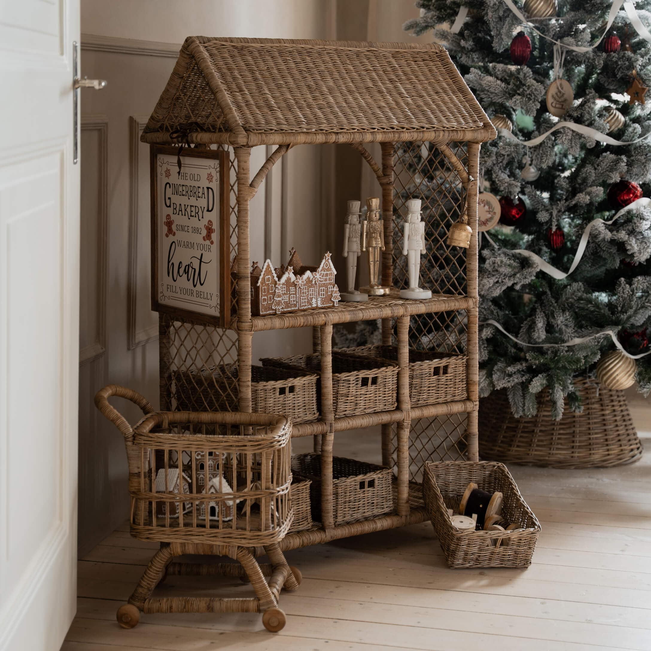 Meuble en rotin naturel avec décorations de Noël et sapin décoré en arrière-plan