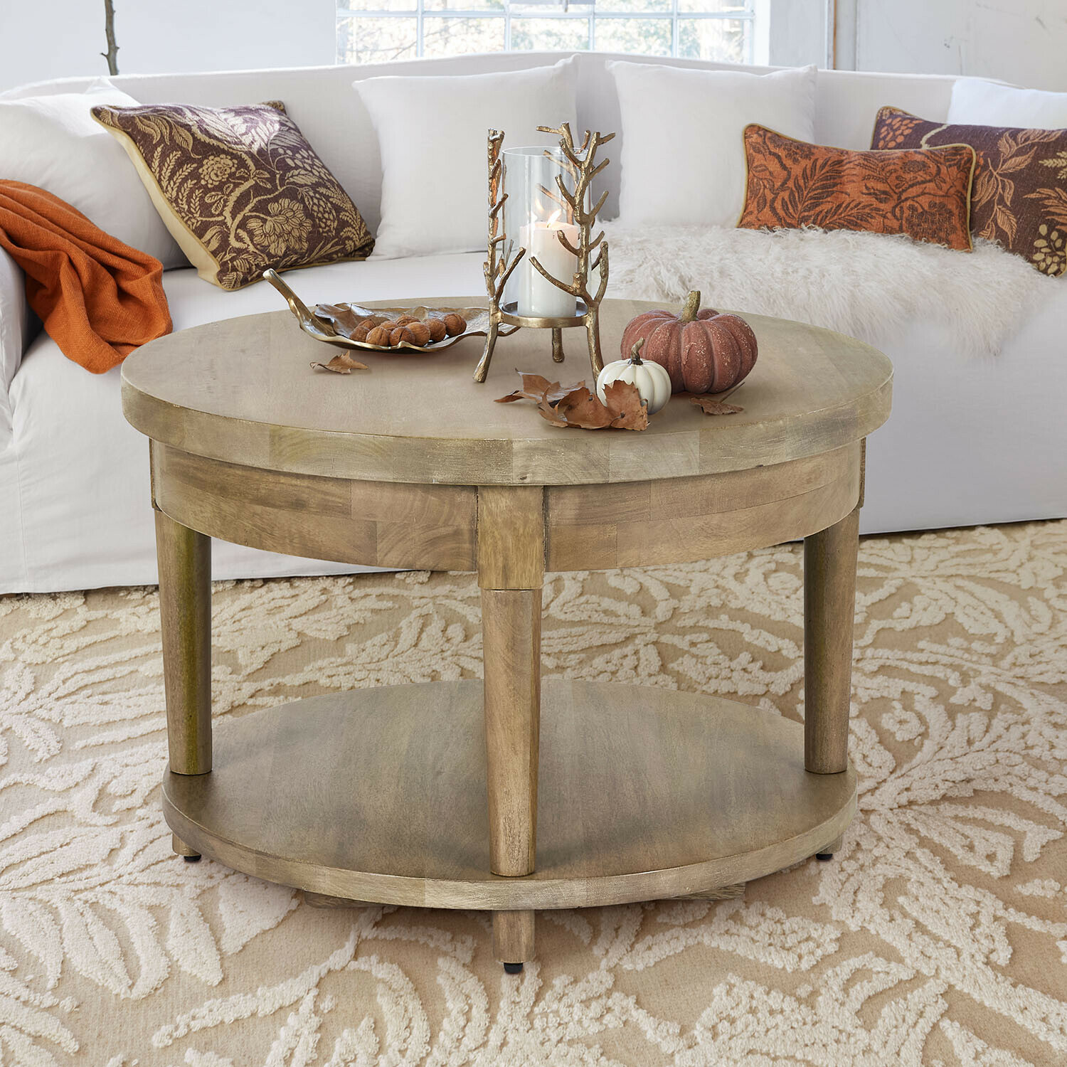 Table basse Talinar Table basse ronde en bois couleur naturelle avec décoration de bougie et citrouilles sur tapis beige