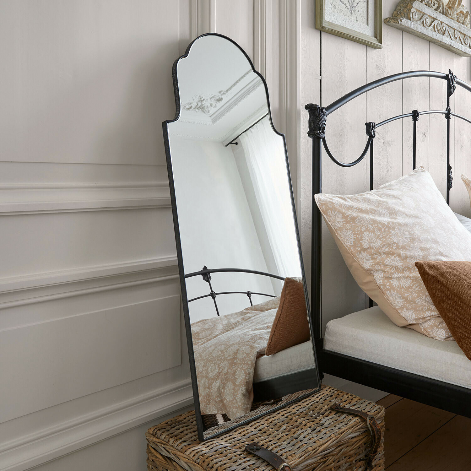 Miroir mural Tavreen Miroir sur pied avec cadre en métal noir décoratif dans une chambre avec lit et coussins beiges