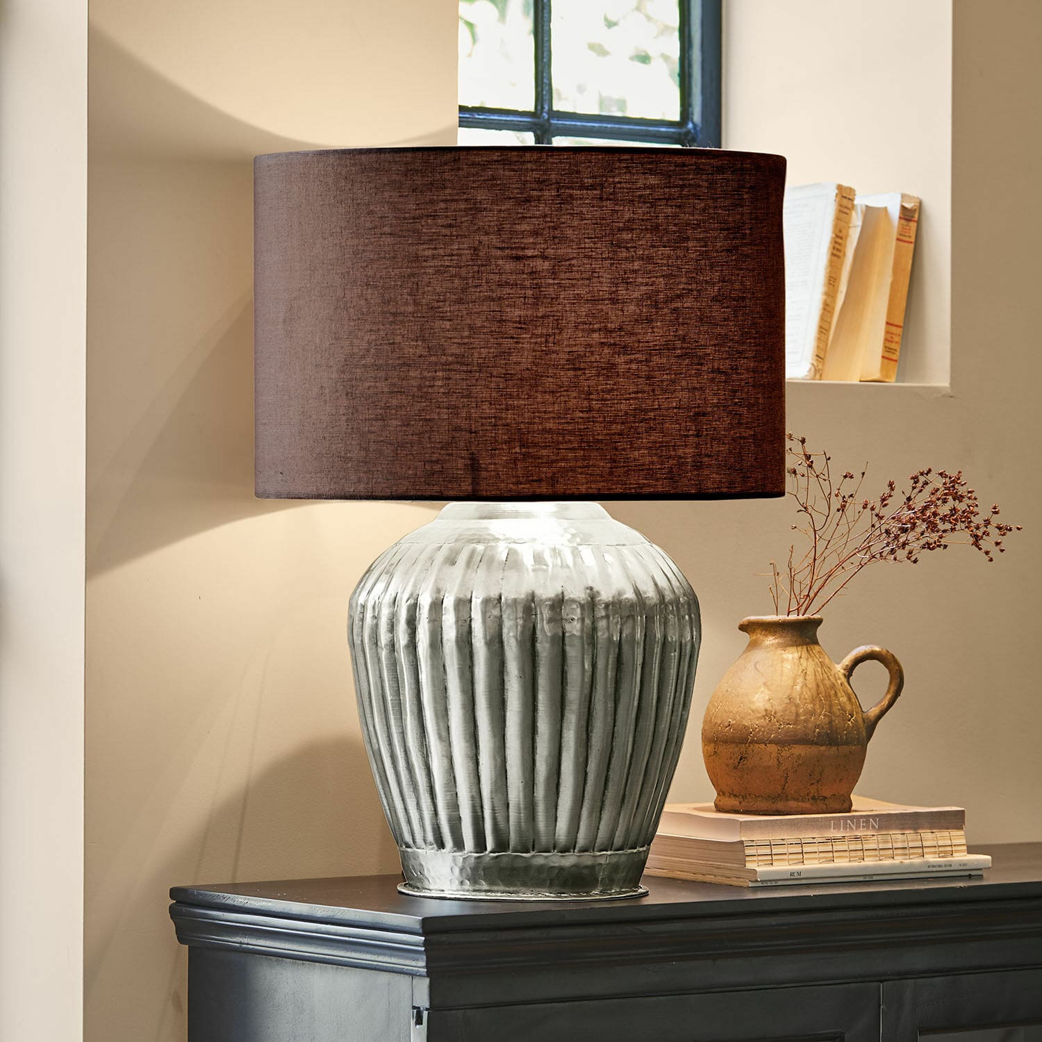 Lampe à poser Fauville Lampe de table avec base en métal argenté et abat-jour marron sur commode sombre