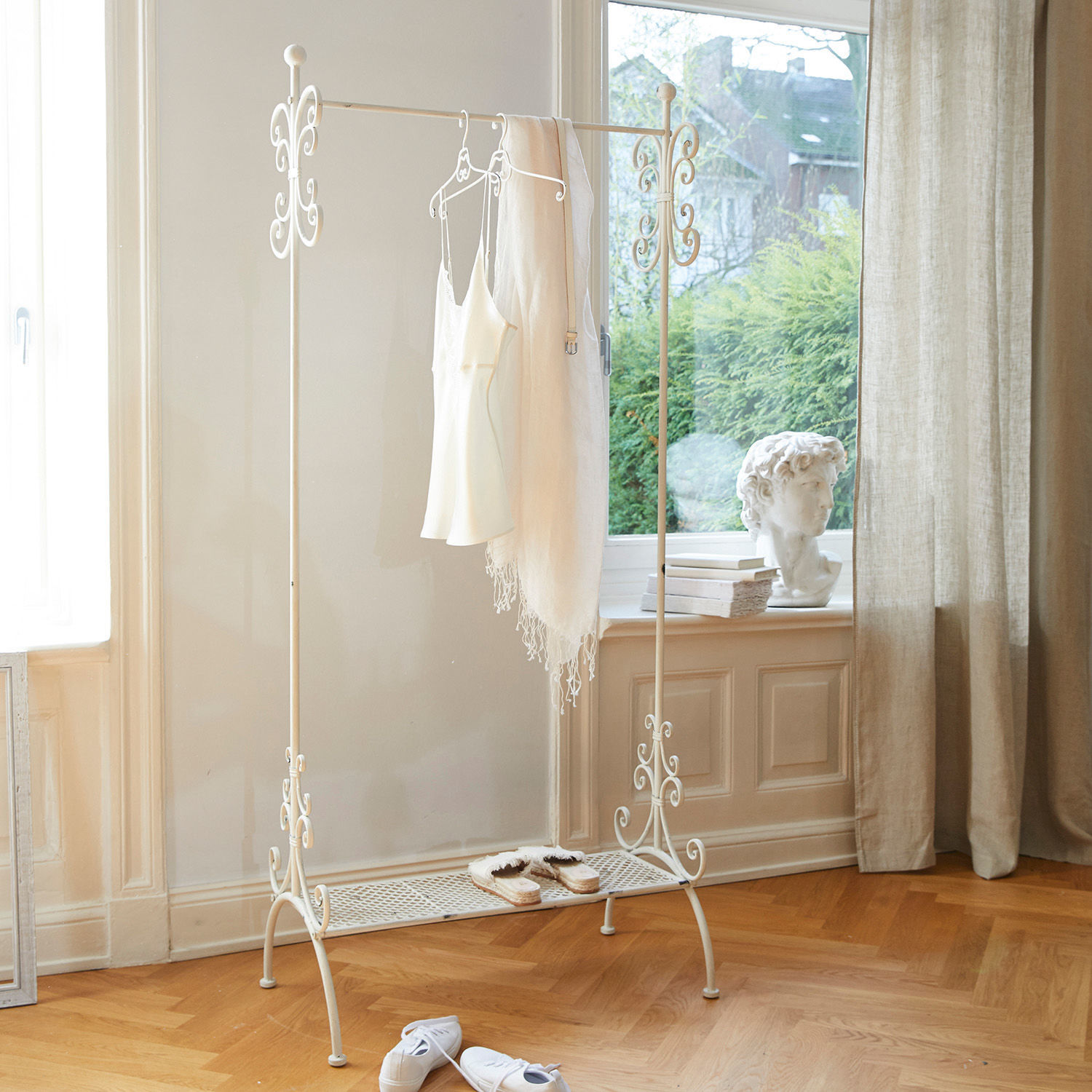 Portant Épinay Porte-vêtements en métal blanc avec détails décoratifs et étagère à chaussures dans une pièce lumineuse