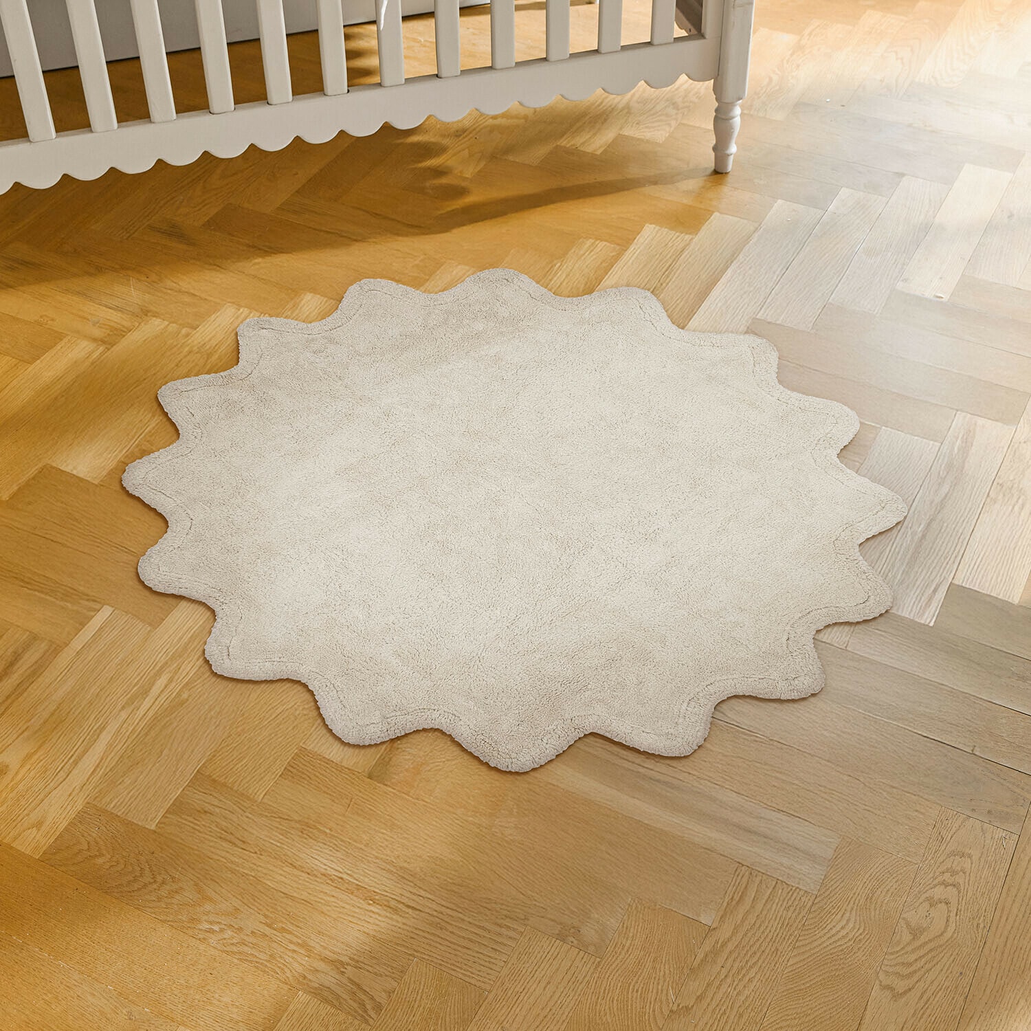 Tapis Wonderfluff Tapis rond beige en matière douce avec bord ondulé posé sur un parquet en bois clair