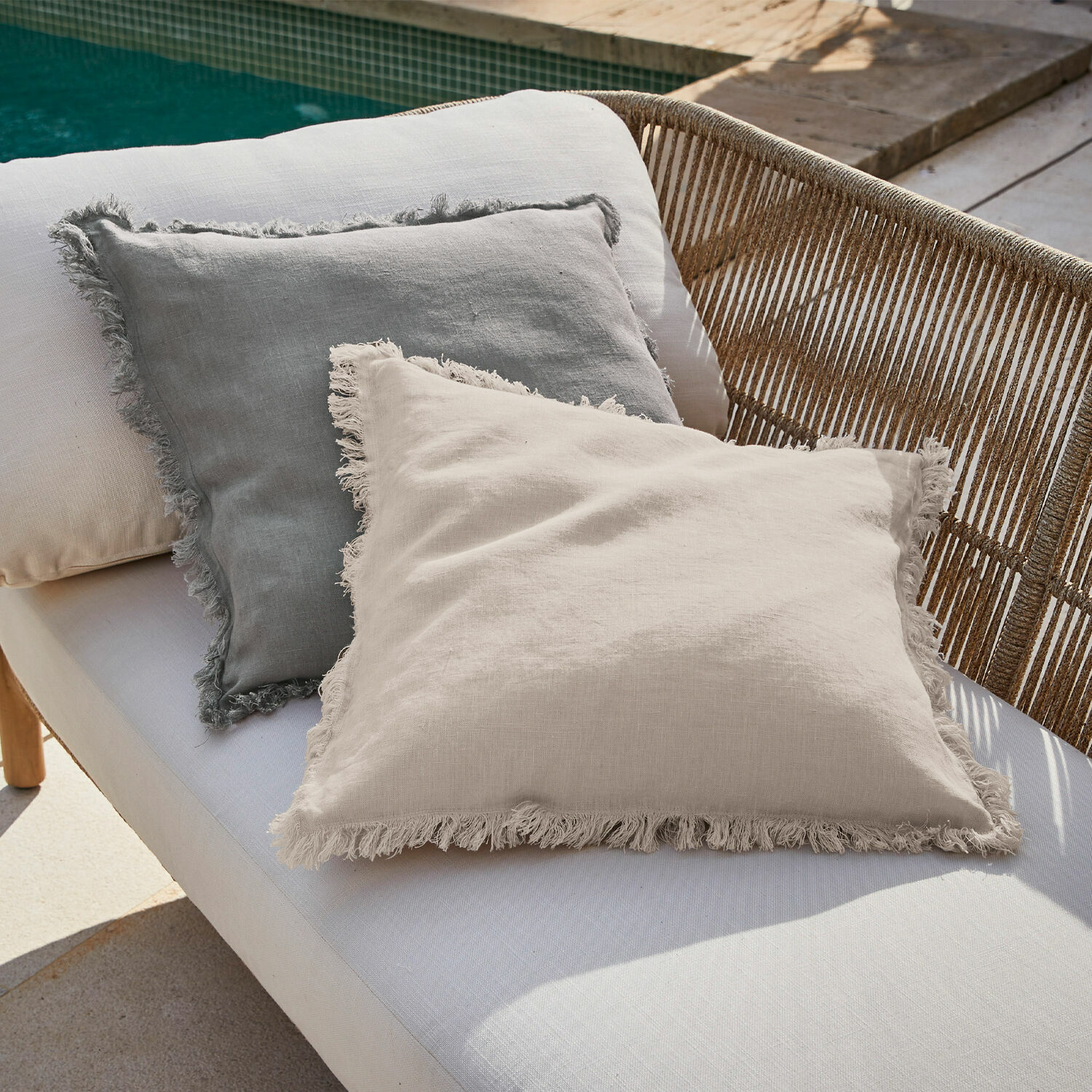 Lot de 2 housses de coussins Quebo Coussins décoratifs en lin beige et gris avec franges sur un canapé d'extérieur près de la piscine