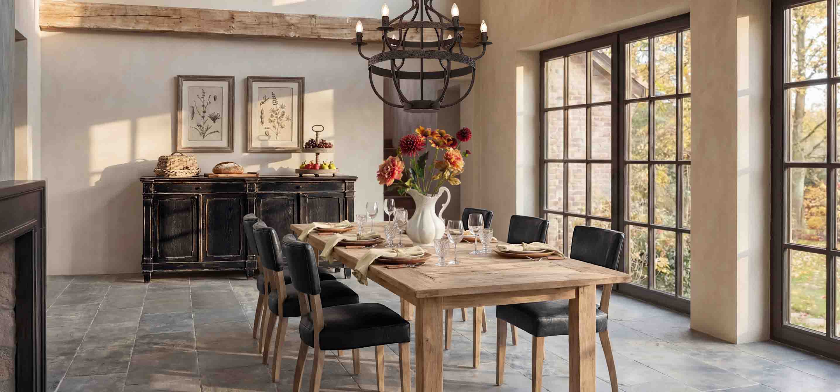 Salle à manger avec table en bois, chaises noires et buffet rustique devant de grandes fenêtres