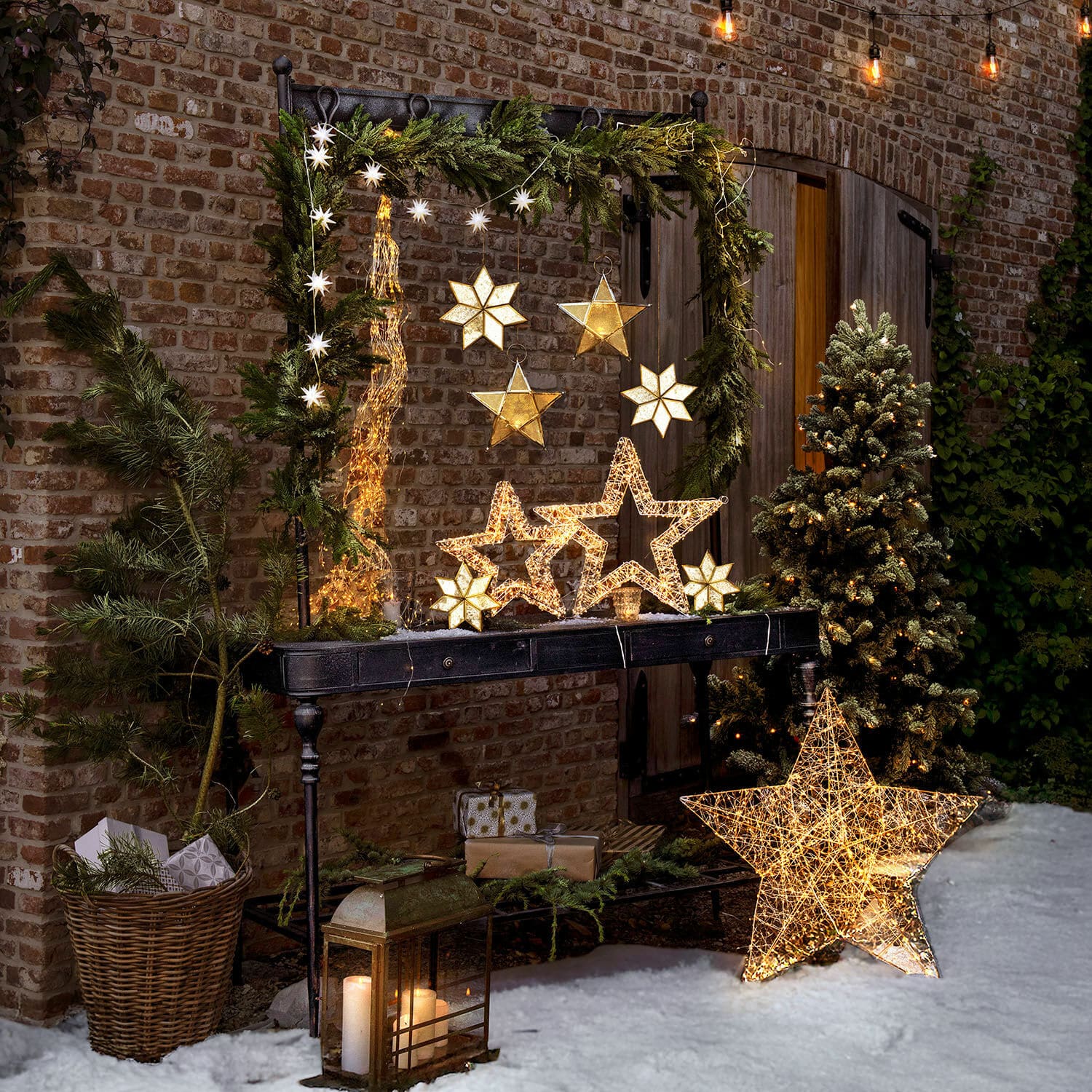 Console Langmore Décorations de Noël lumineuses en forme d'étoiles LED sur une table noire dans un jardin enneigé avec sapin