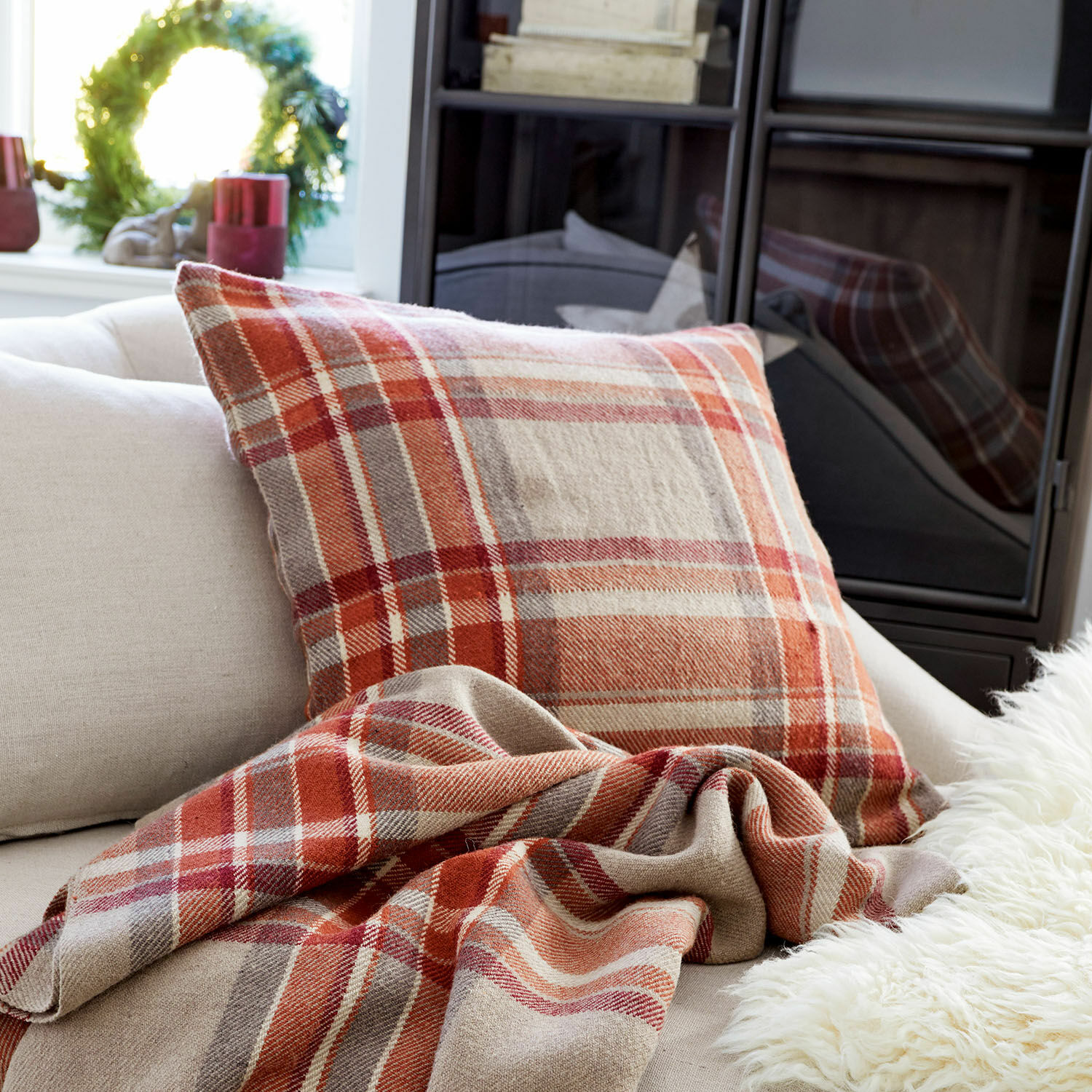 Housse de coussin Tartan Coussin et plaid à carreaux rouges et beiges sur un canapé clair dans un salon cosy