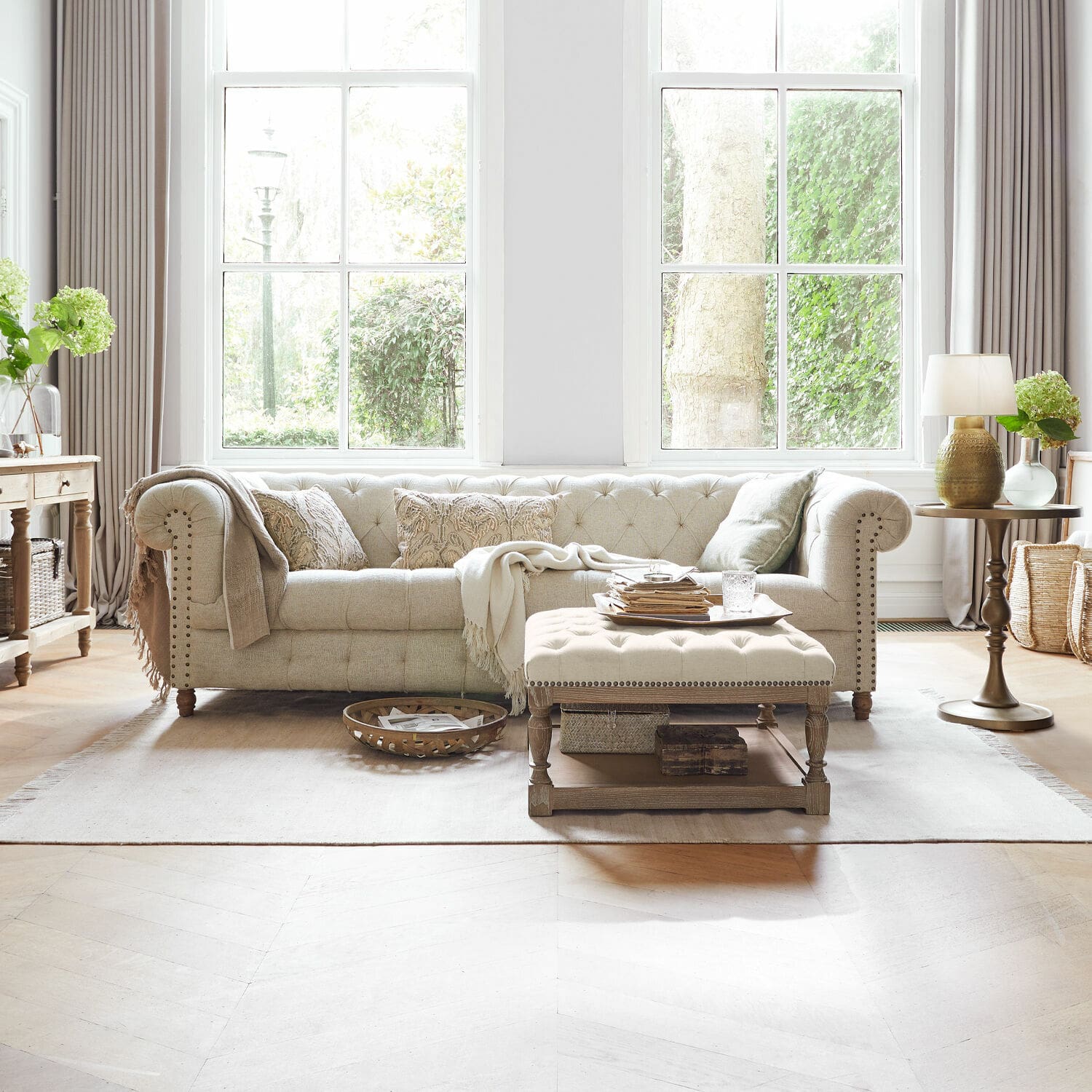 Canapé Parpeville Canapé beige en tissu capitonné avec coussins brodés et table basse en bois dans un salon lumineux