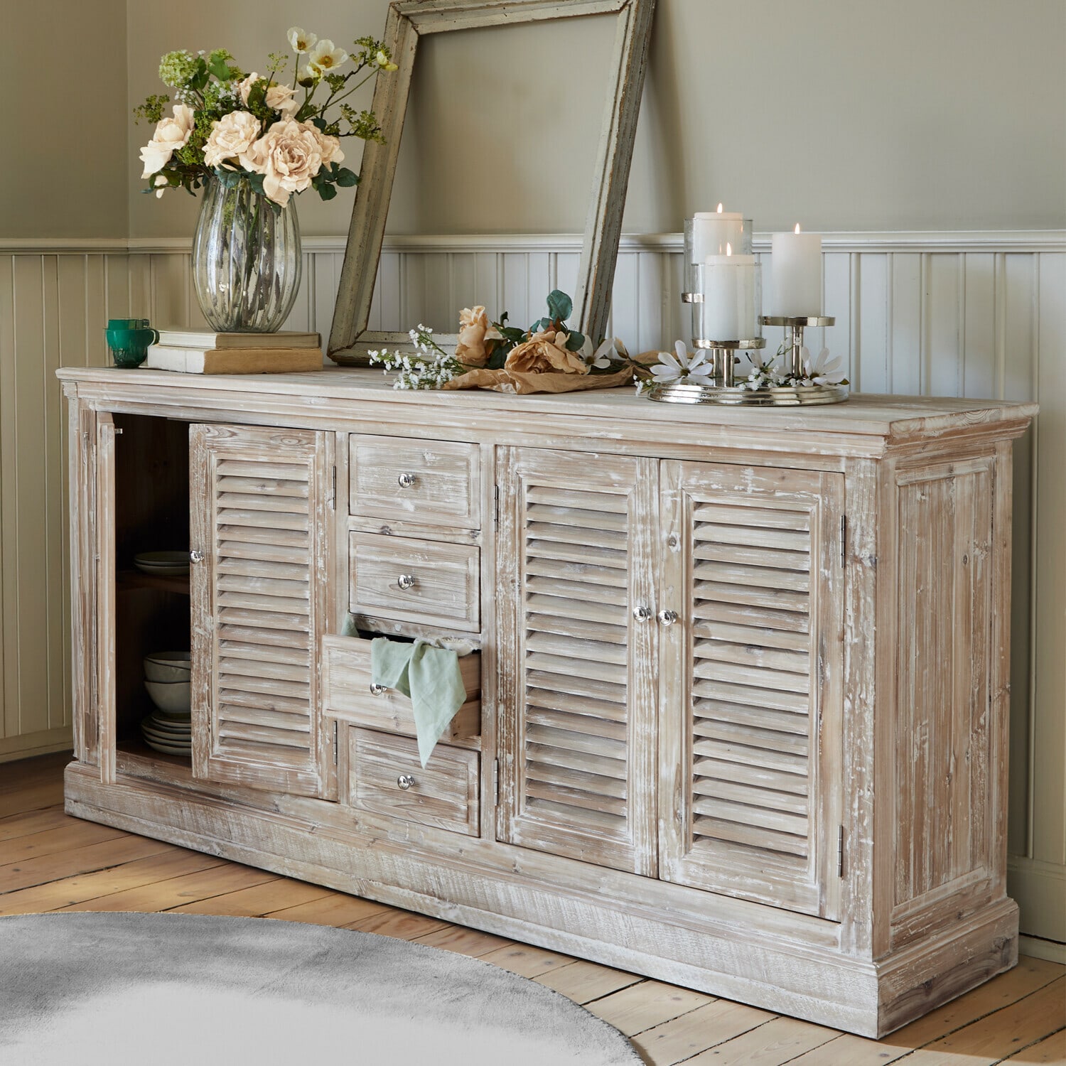Commode Houston Buffet rustique en bois blanchi avec décorations florales et bougies dans un salon lumineux
