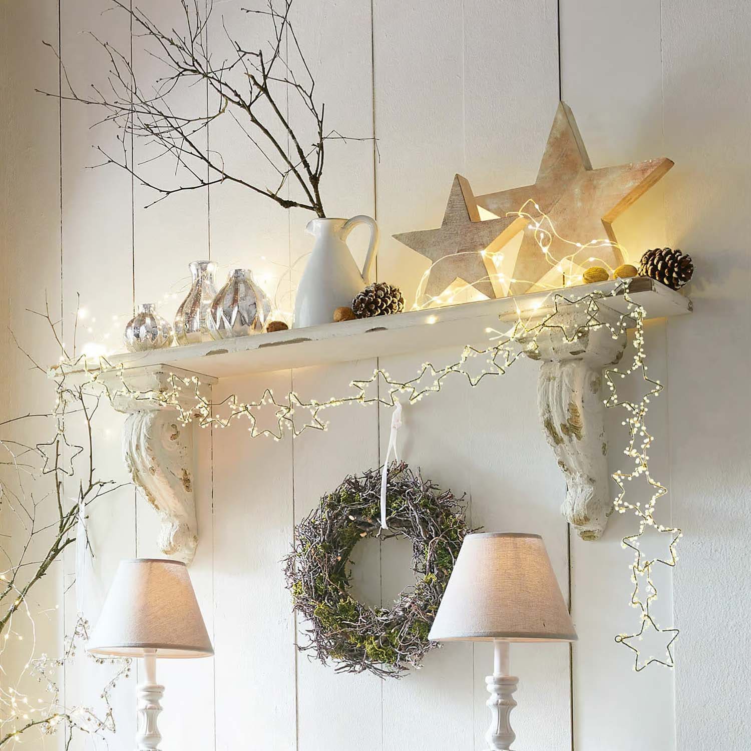 Étagère blanche décorative avec guirlande lumineuse en forme d'étoiles, couronne et lampes de table