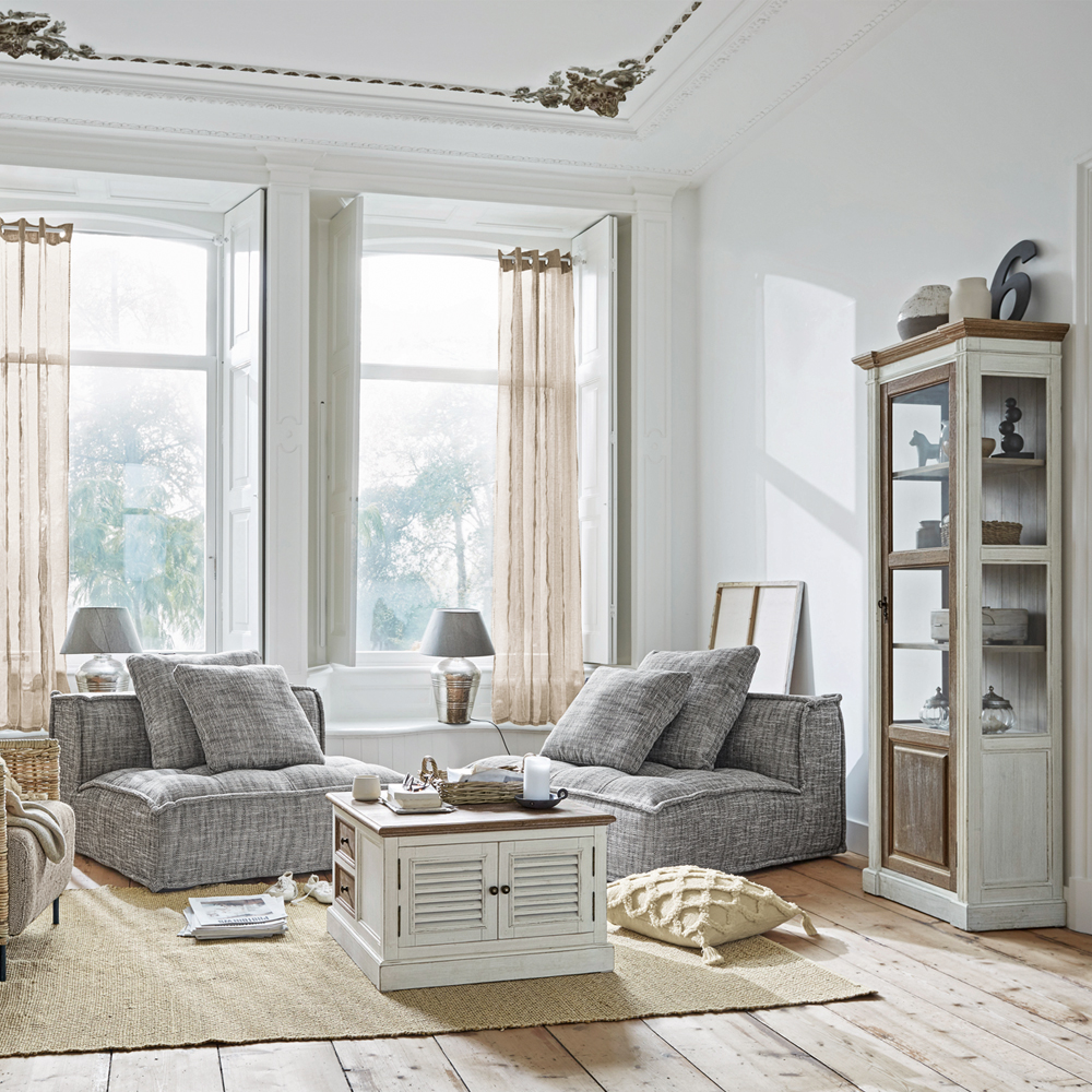Salon lumineux avec fauteuils gris et meuble en bois blanc sur tapis en jute, style scandinave moderne