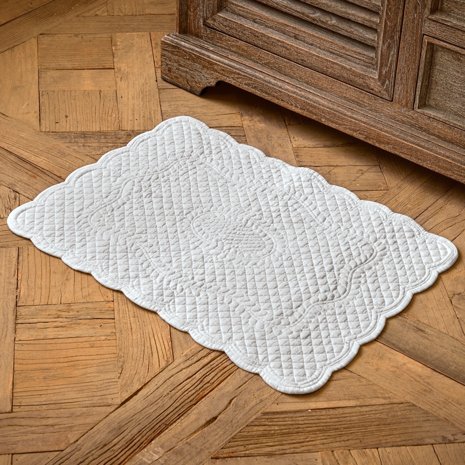Tapis de bain Meggie Tapis en coton matelassé blanc avec motif décoratif sur parquet en bois, accessoire déco intérieur