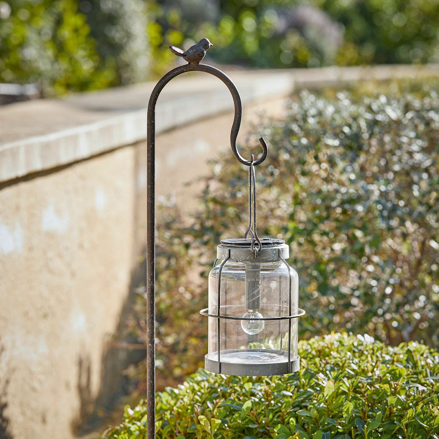 Lanterne solaire Anières Support en métal avec lanterne en verre et métal dans un jardin, décoration avec oiseau en haut