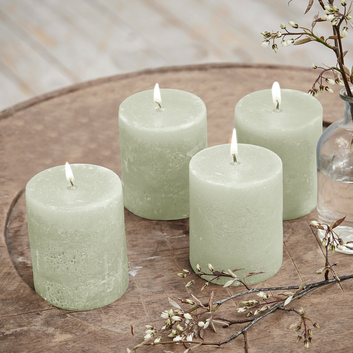 Lot de 4 bougies Virrans Ensemble de quatre bougies vertes en cire sur un plateau en bois avec branches décoratives