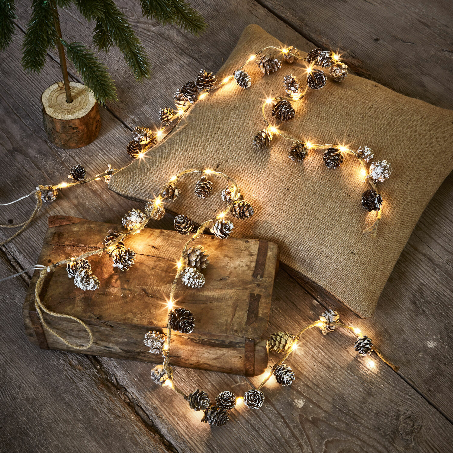 Lot de 2 guirlandes lumineuses LED Crane Guirlande lumineuse avec pommes de pin et lumière chaude sur table en bois et coussin en lin