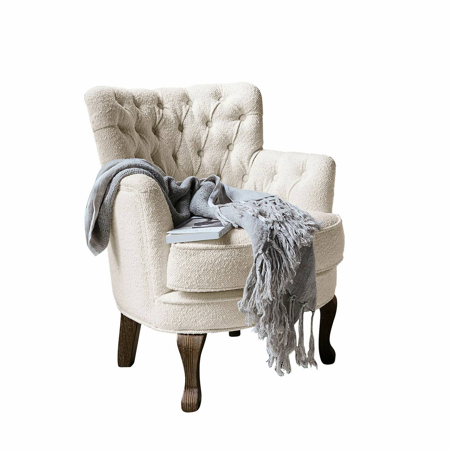 Fauteuil Calgary Fauteuil beige en tissu bouclé avec pieds en bois foncé, couverture grise et livre posé dessus