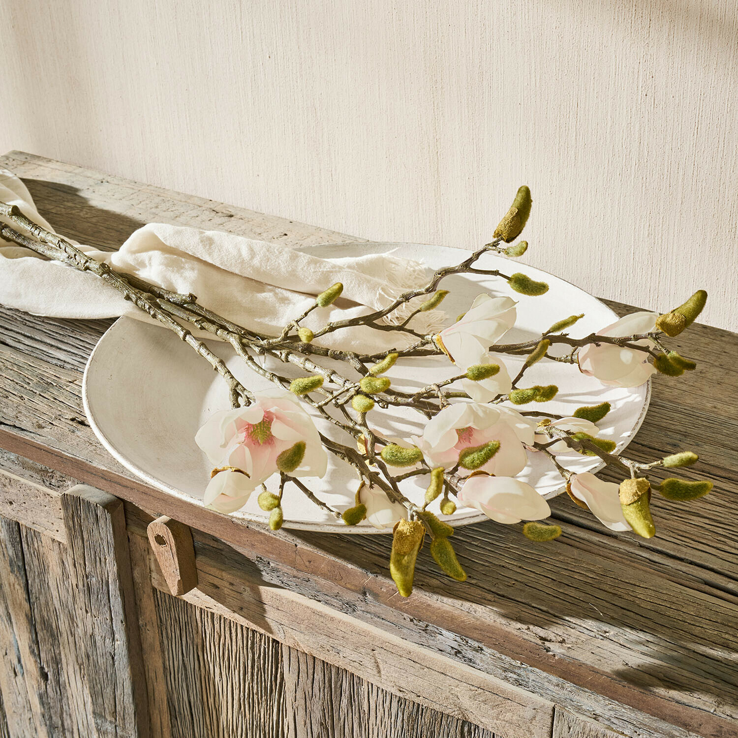 Lot de 2 fleurs décoratives Aurélines Branches de magnolia avec fleurs blanches et bourgeons verts sur une table en bois rustique avec assiette blanche