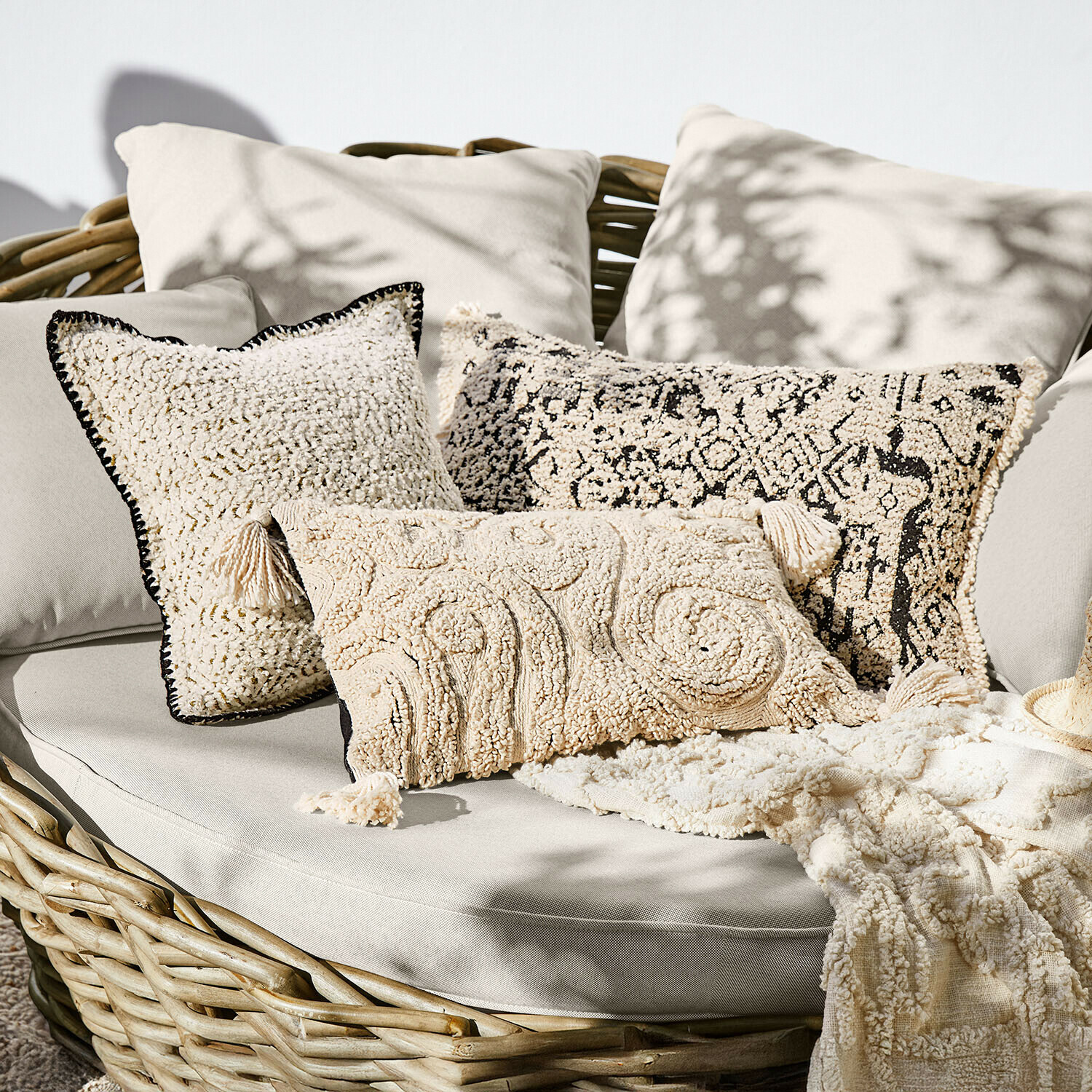 Ensemble de coussins décoratifs crème en tissu doux sur canapé en osier, style bohème