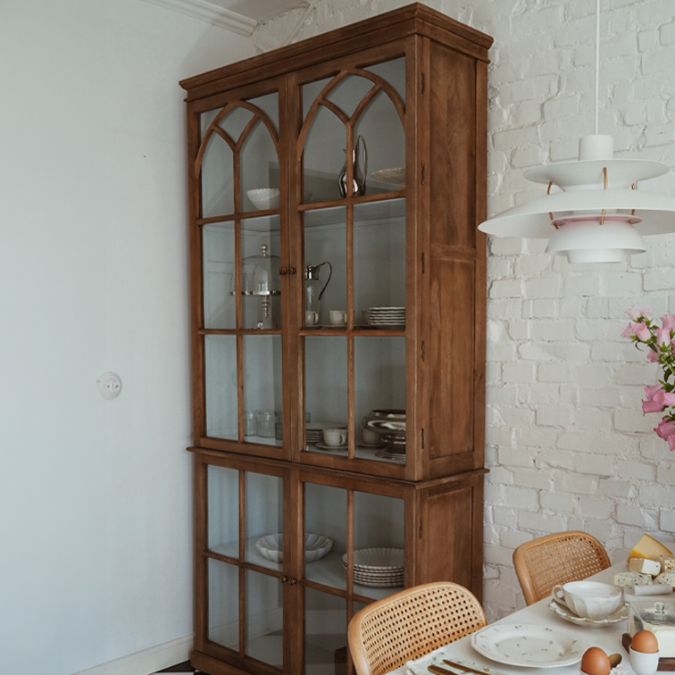 Vitrine en bois avec portes vitrées style vintage dans une salle à manger avec mur en briques blanches