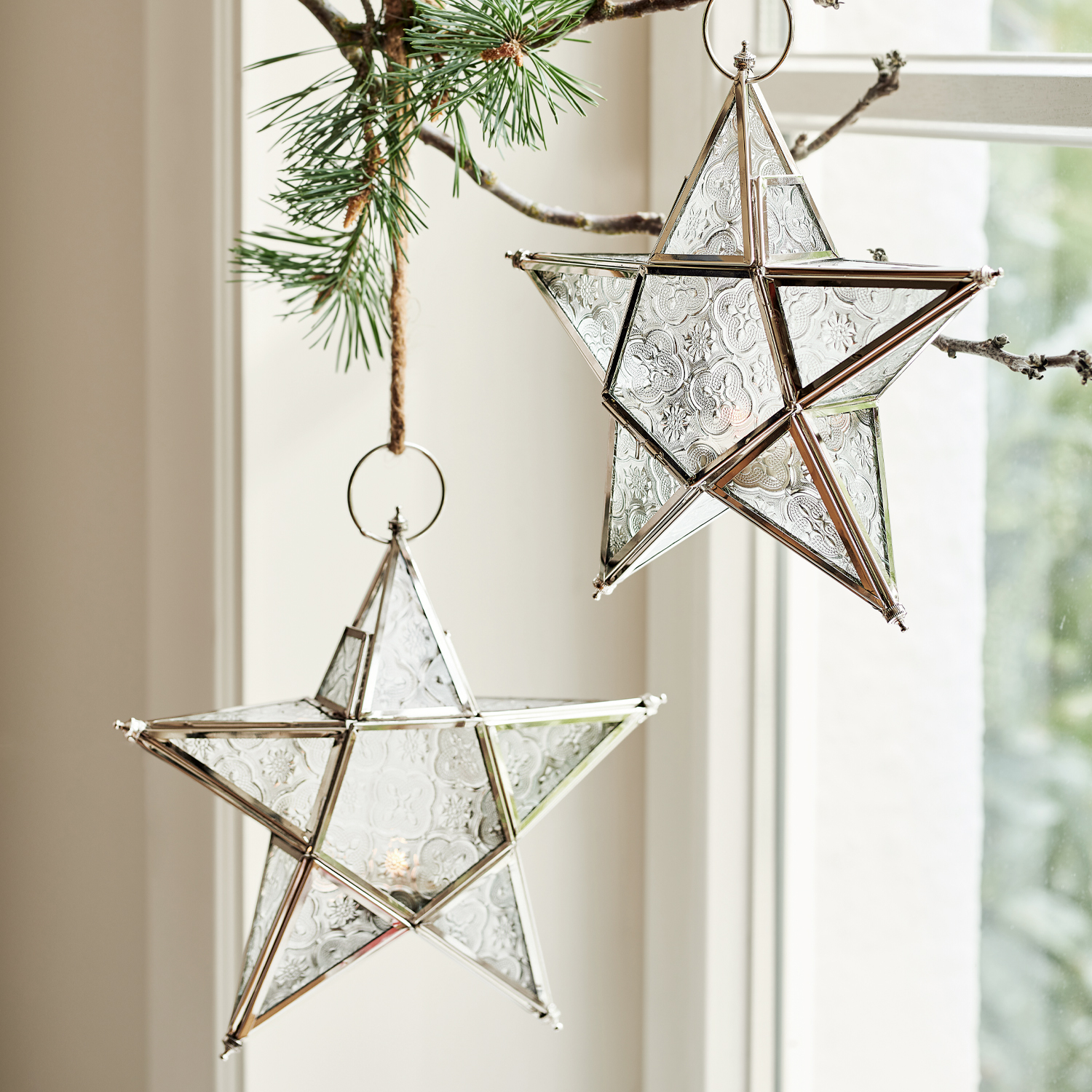 Étoiles décoratives en verre et métal avec motifs, suspendues près de la fenêtre, décoration festive
