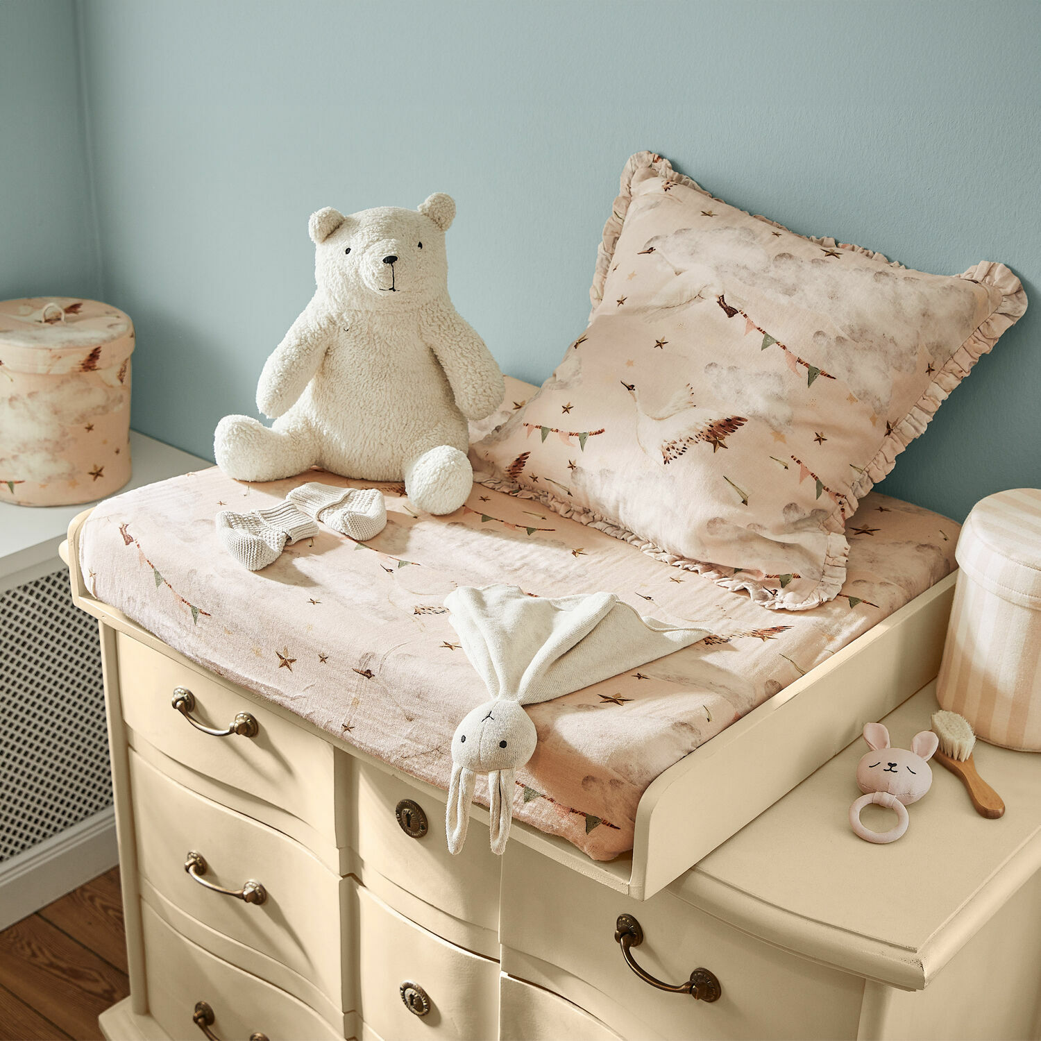 Plan à langer Aiguillon Table à langer beige sur commode avec housse rose et peluches dans une chambre d'enfant
