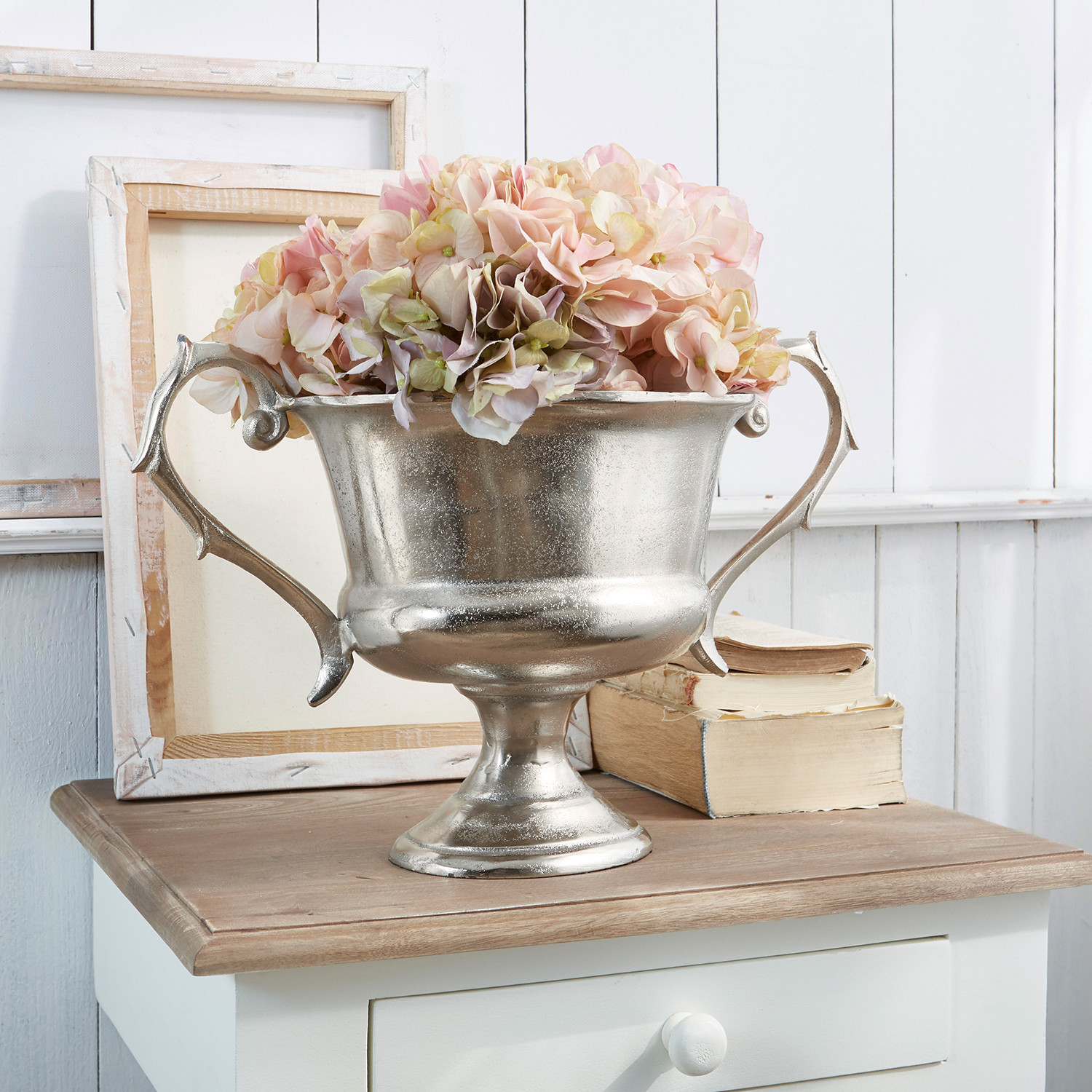 Coupe Espère Coupe en métal argenté avec poignées et fleurs roses sur table en bois, décoration intérieure