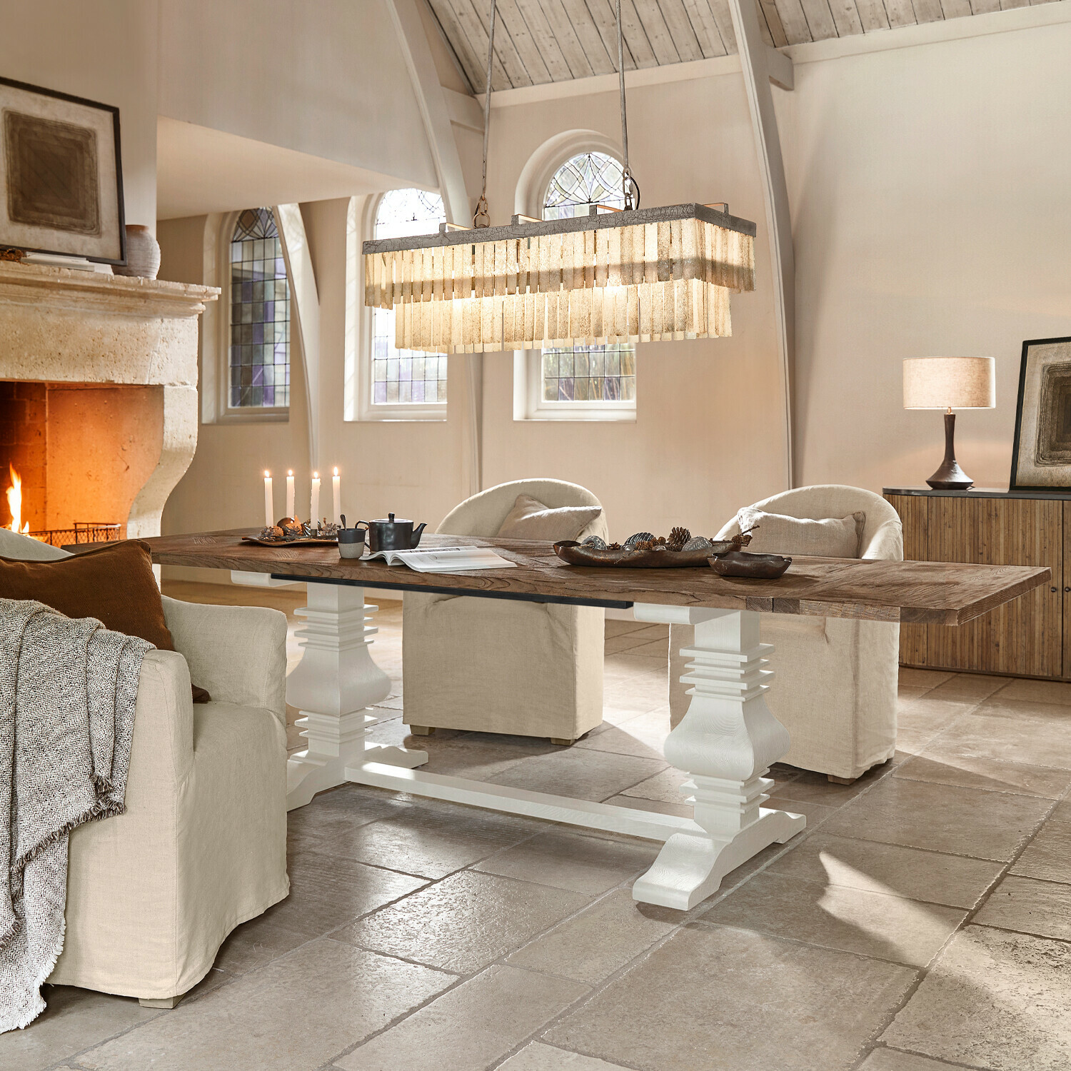 Table Quillancourt Grande table en bois avec pied blanc dans un salon lumineux avec cheminée et fauteuils beige