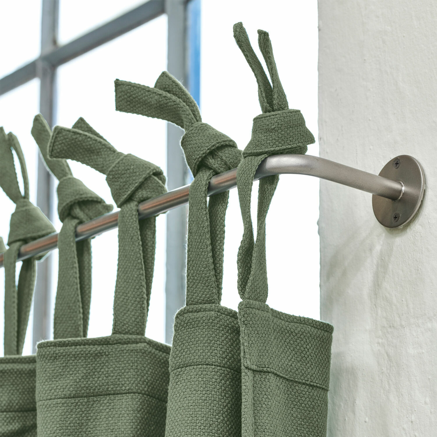 Tringle à rideaux Omara Rideaux verts en coton suspendus sur une tringle métallique dans un intérieur moderne
